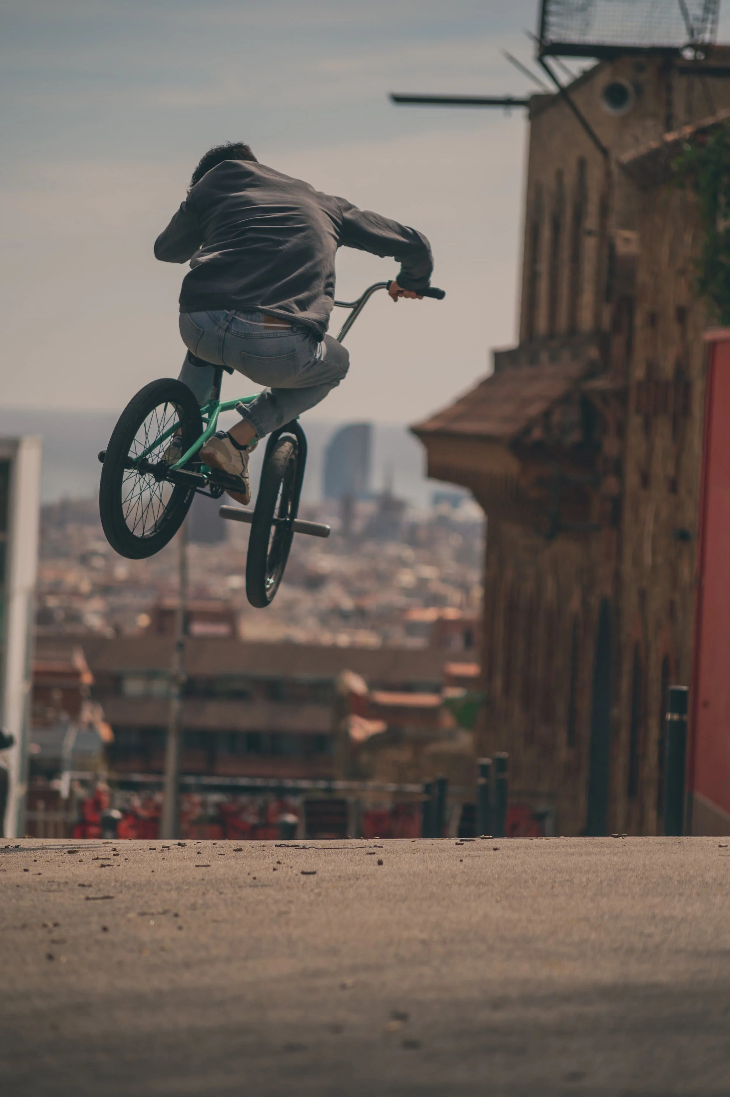 Anatole Rahain fait du BMX en sautant dans une ville, avec des immeubles en arrière-plan.
