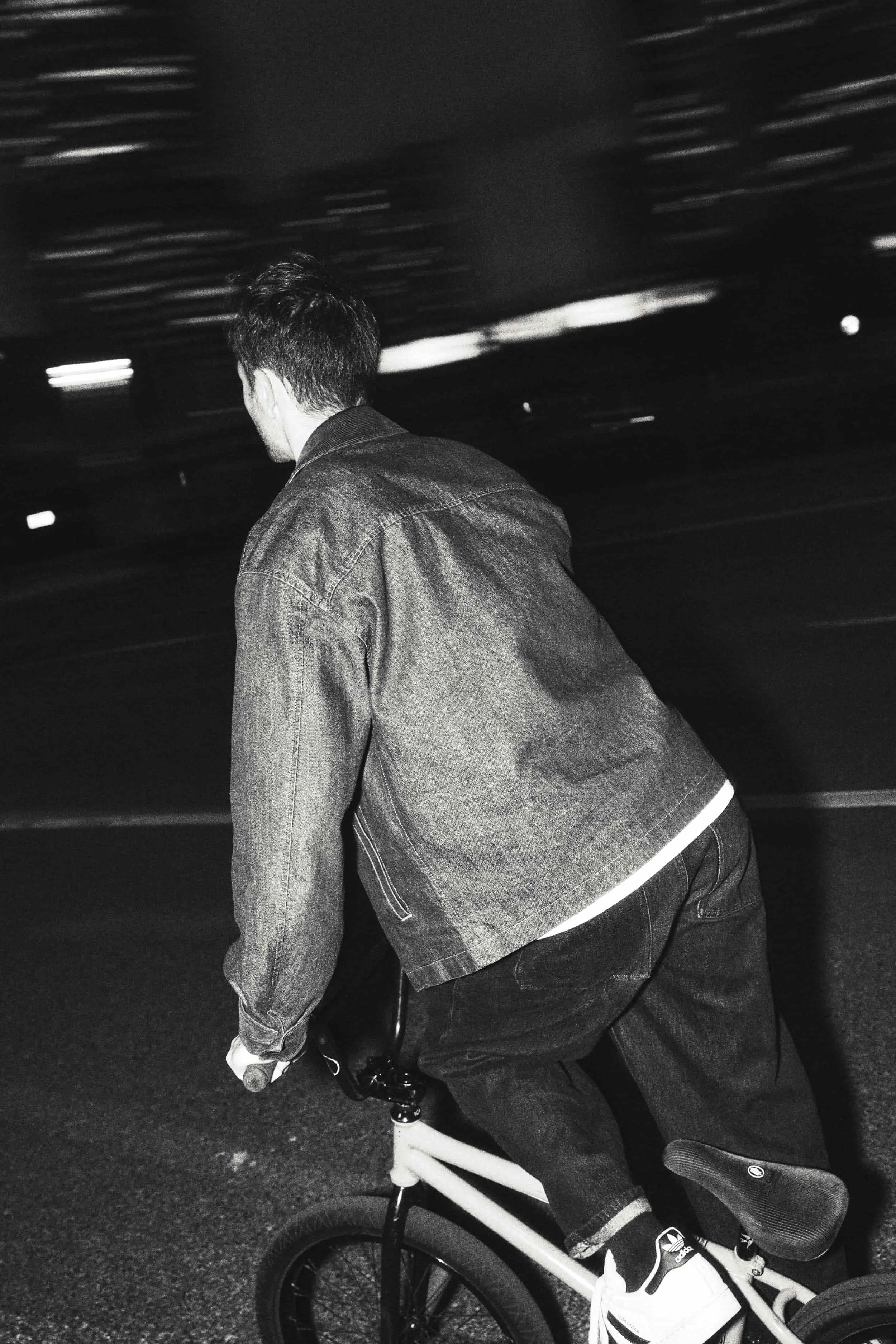 Anatole Rahain de nuit sur son BMX, en train de rouler, avec un vélo blanc, un outfit streetwear et des baskets Adidas