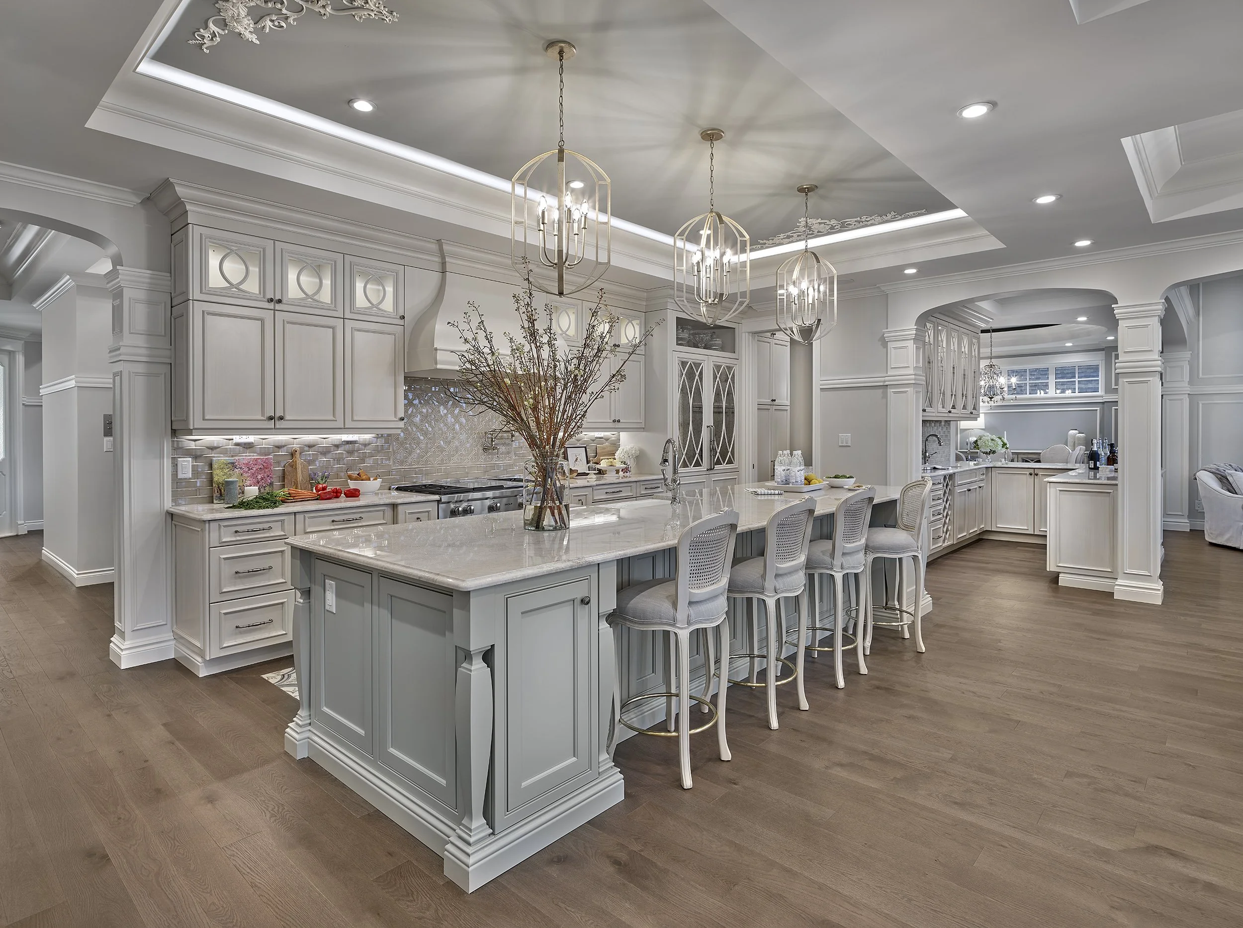 Modern kitchen with white cabinetry, island with seating, pendant lighting, and hardwood floors.