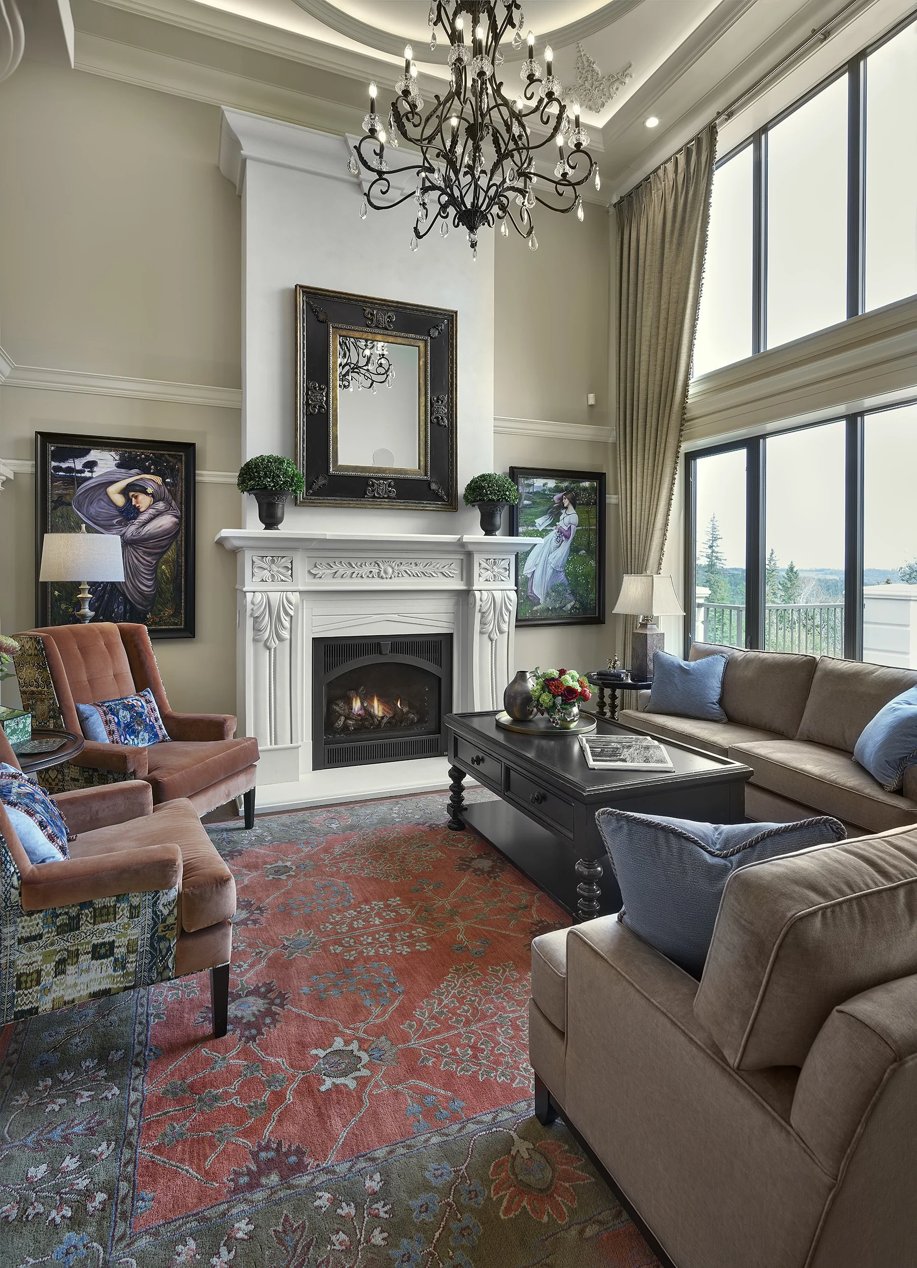 Living room with large windows, high ceiling, chandelier, fireplace, framed artworks, beige and brown furniture, black coffee table, colorful rug, and decorative items.