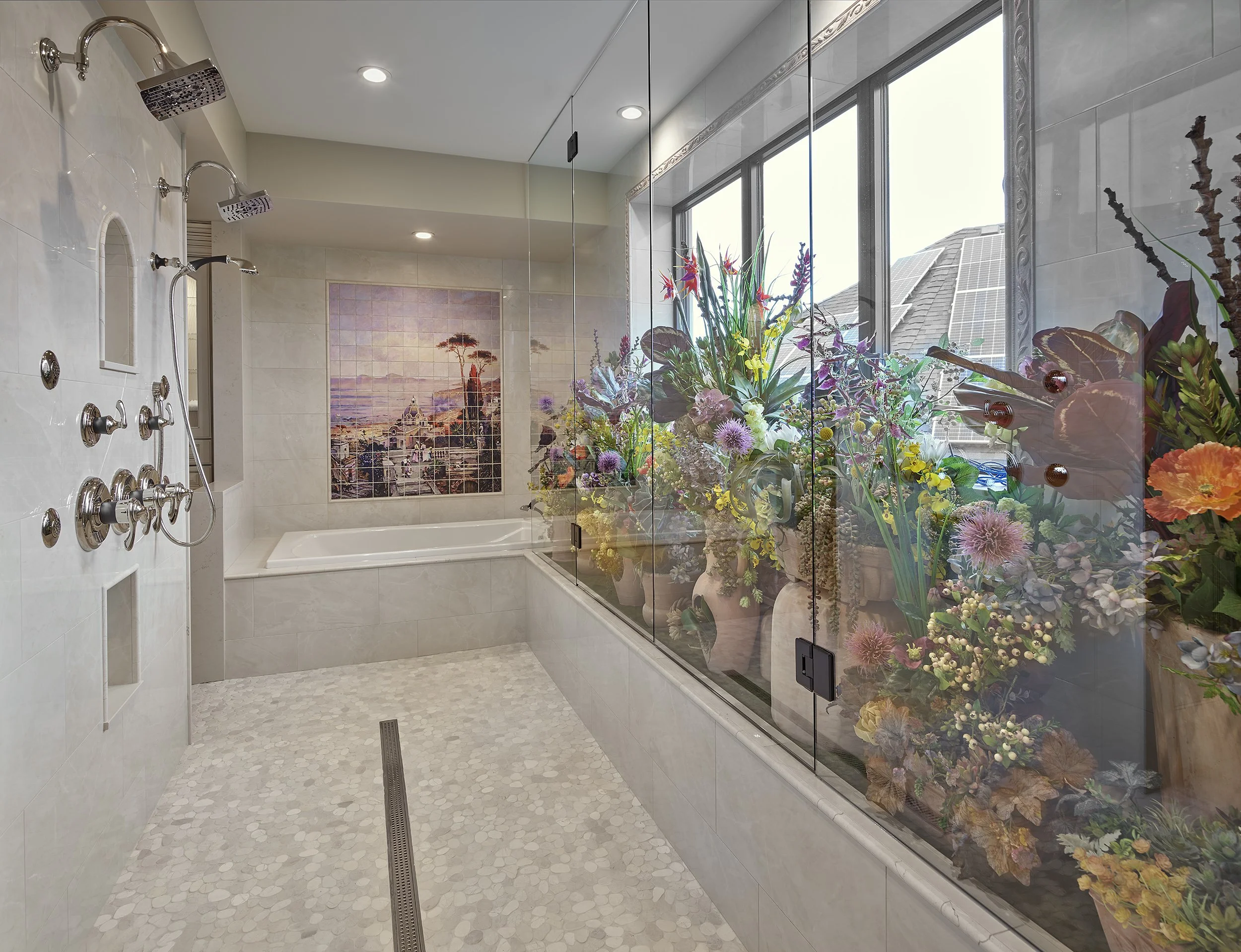 Luxury bathroom with multiple showerheads, a bathtub, and large windows filled with colorful flower arrangements.