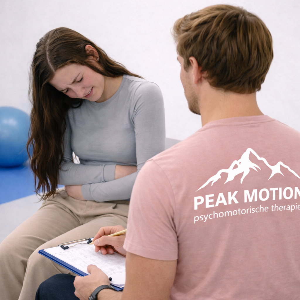 Gesprek tussen een therapeut en een persoon in een oefenruimte, met het Peak Motion-logo zichtbaar op het shirt van de therapeut.