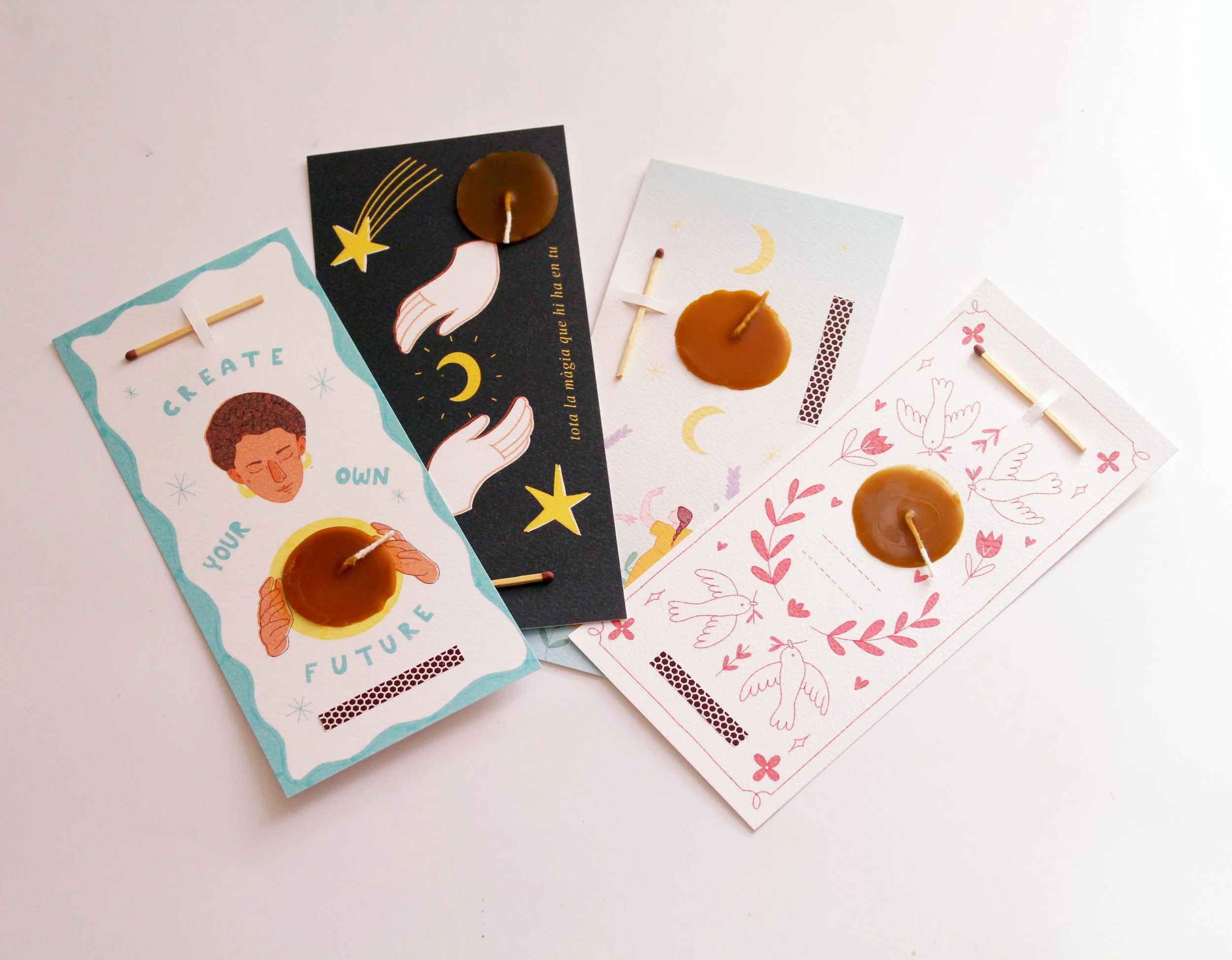 Cuatro tarjetas decorativas con velas y cerillas sobre una superficie blanca, cada una con diferentes ilustraciones y mensajes positivos.