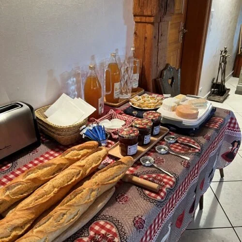 Tafel met baguettes, confitures, boter, toast, sap, en saus, klaar voor ontbijt bij het chateau van Ruhlmann-Schutz