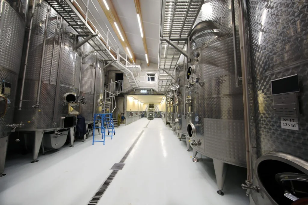 Binnenkant van een wijnmakerij met grote stalen vaten en een witte vloer bij het chateau van Ruhlmann-Schutz
