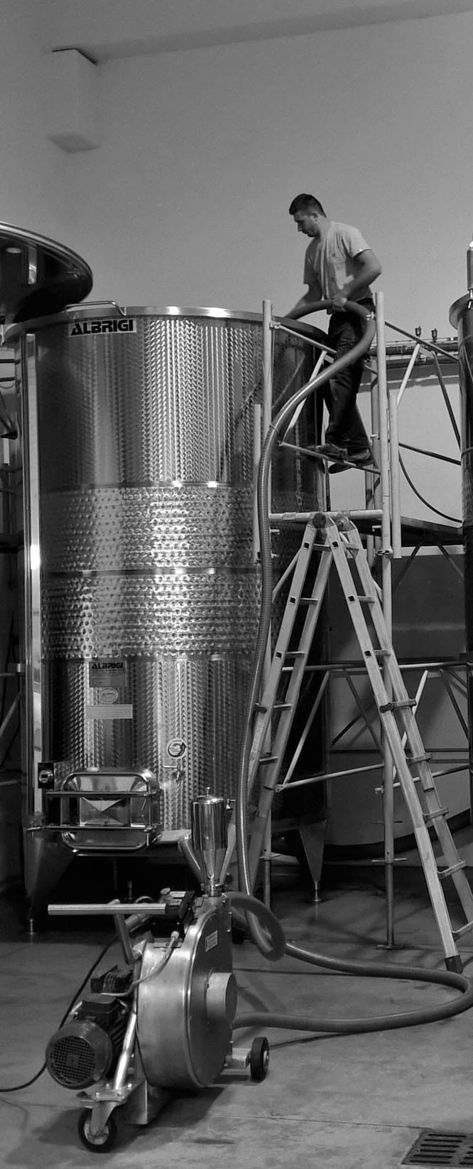 Foto van een van de wijnmakers bij de fermentatieketel bij Bonfanti