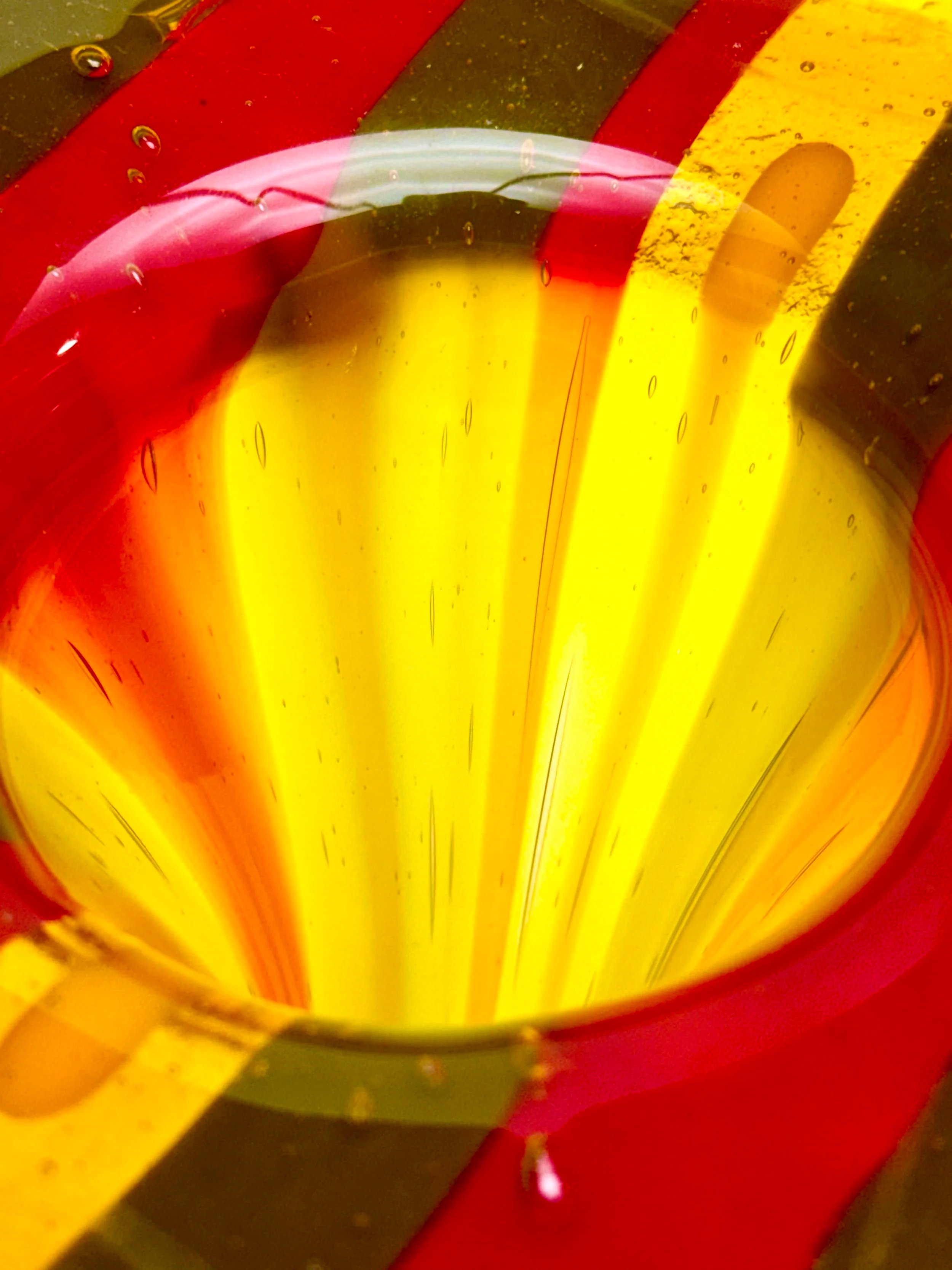 A close-up shot of a colorful object with red, yellow, and black stripes, and a yellow glow in the center, possibly a part of a decorated item or toy.