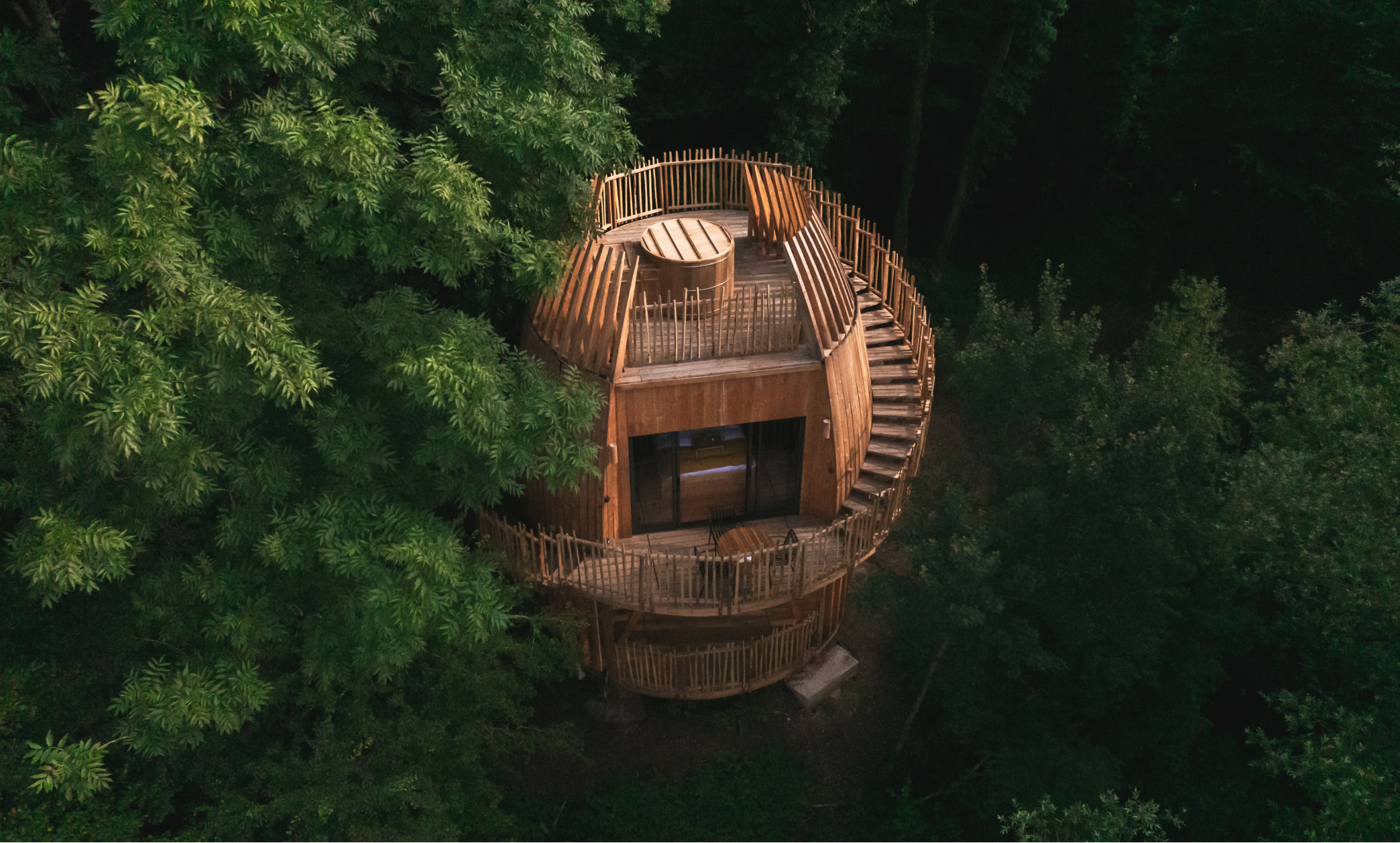 Cabane ronde en bois entourée de forêts, vue aérienne.