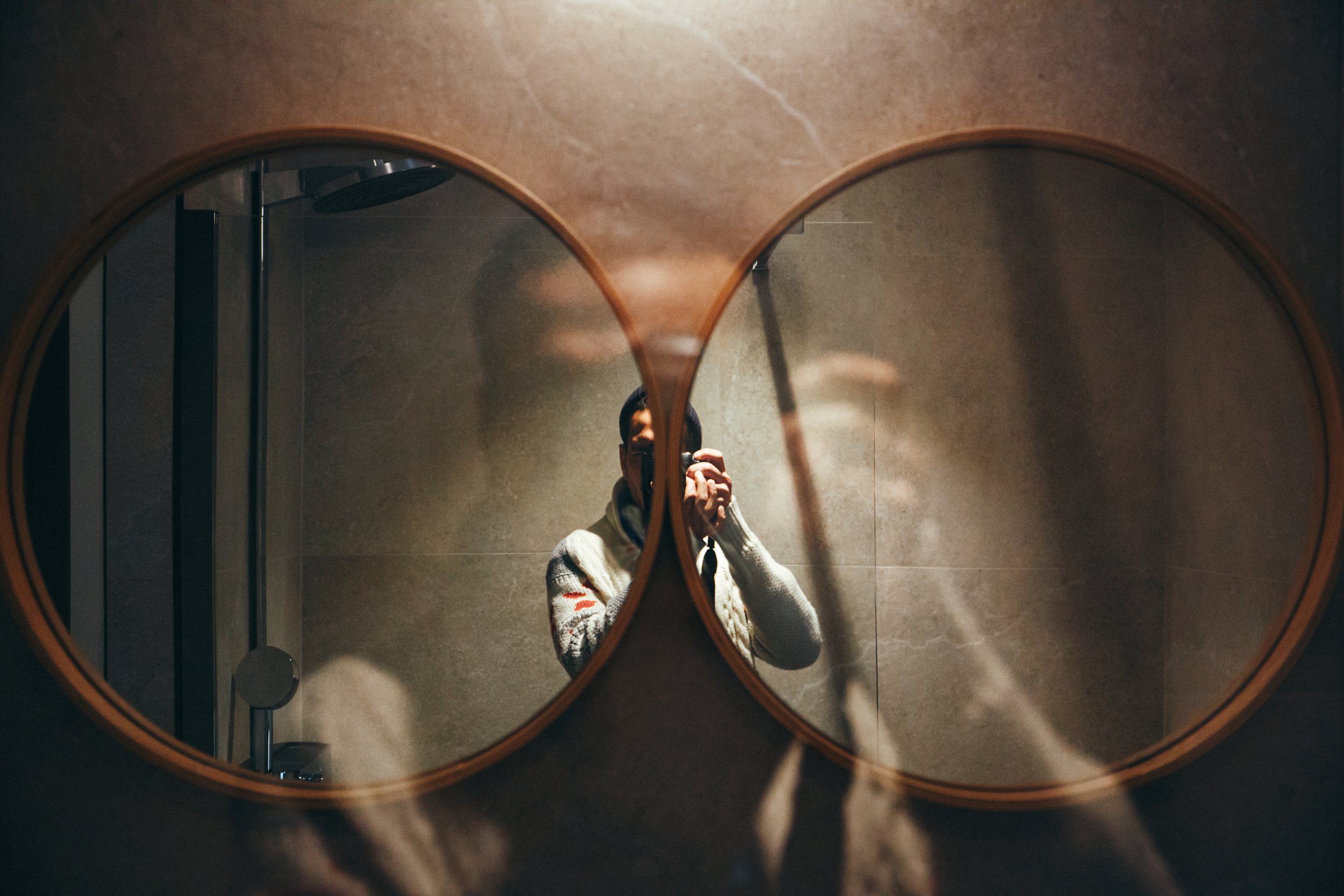 Photo d'une personne qui se prend en selfie dans un miroir rond dans une salle de bain.