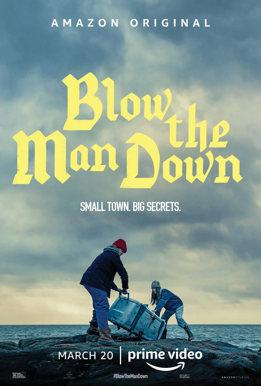 Movie poster for 'Blow the Man Down' featuring two children on a rocky shore, pushing a large metal container into the water under a cloudy sky. The poster includes text indicating it is an Amazon Original, with a release date of March 20 on Prime Vi