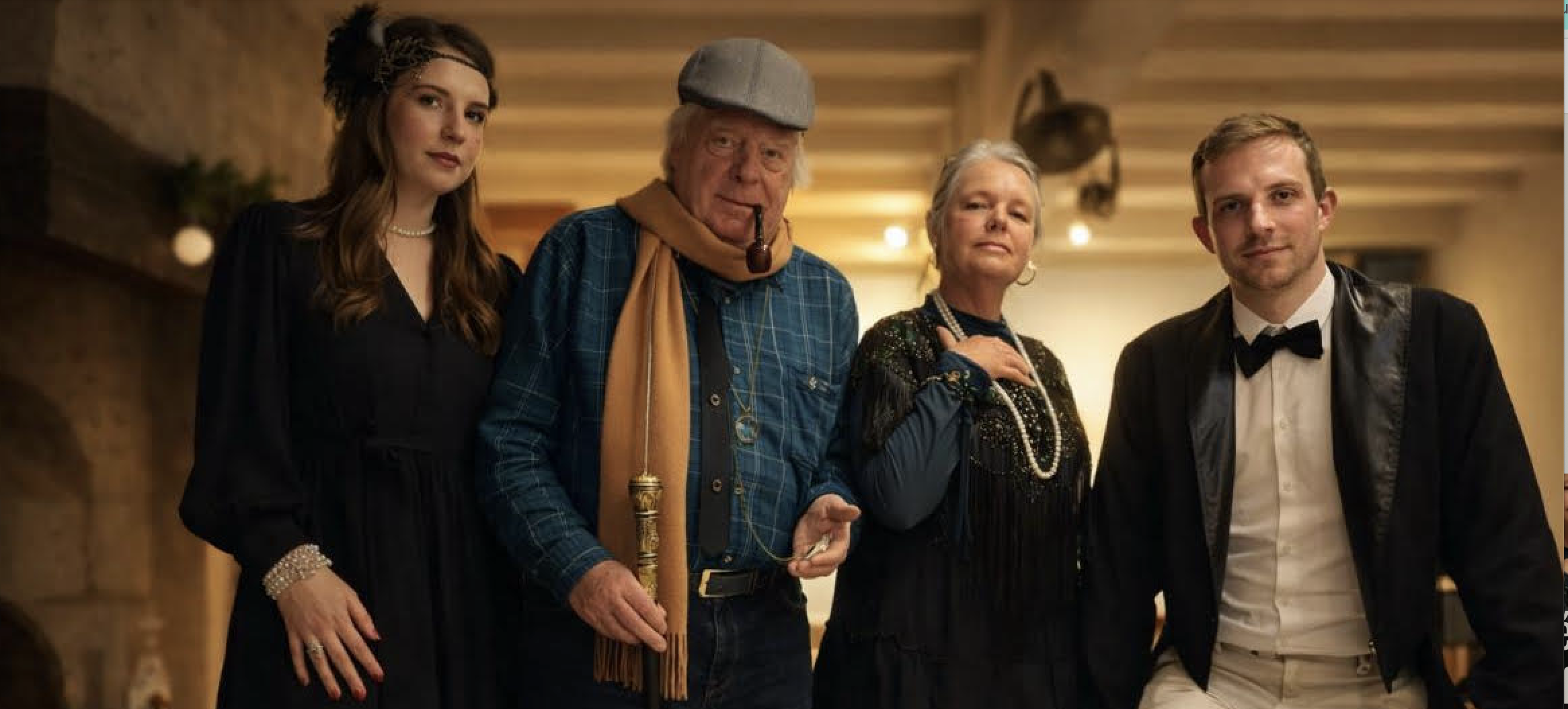 Quatre personnes habillées élégamment, probablement lors d'une fête ou d'un événement, dans un intérieur chaleureux avec un plafond en bois.