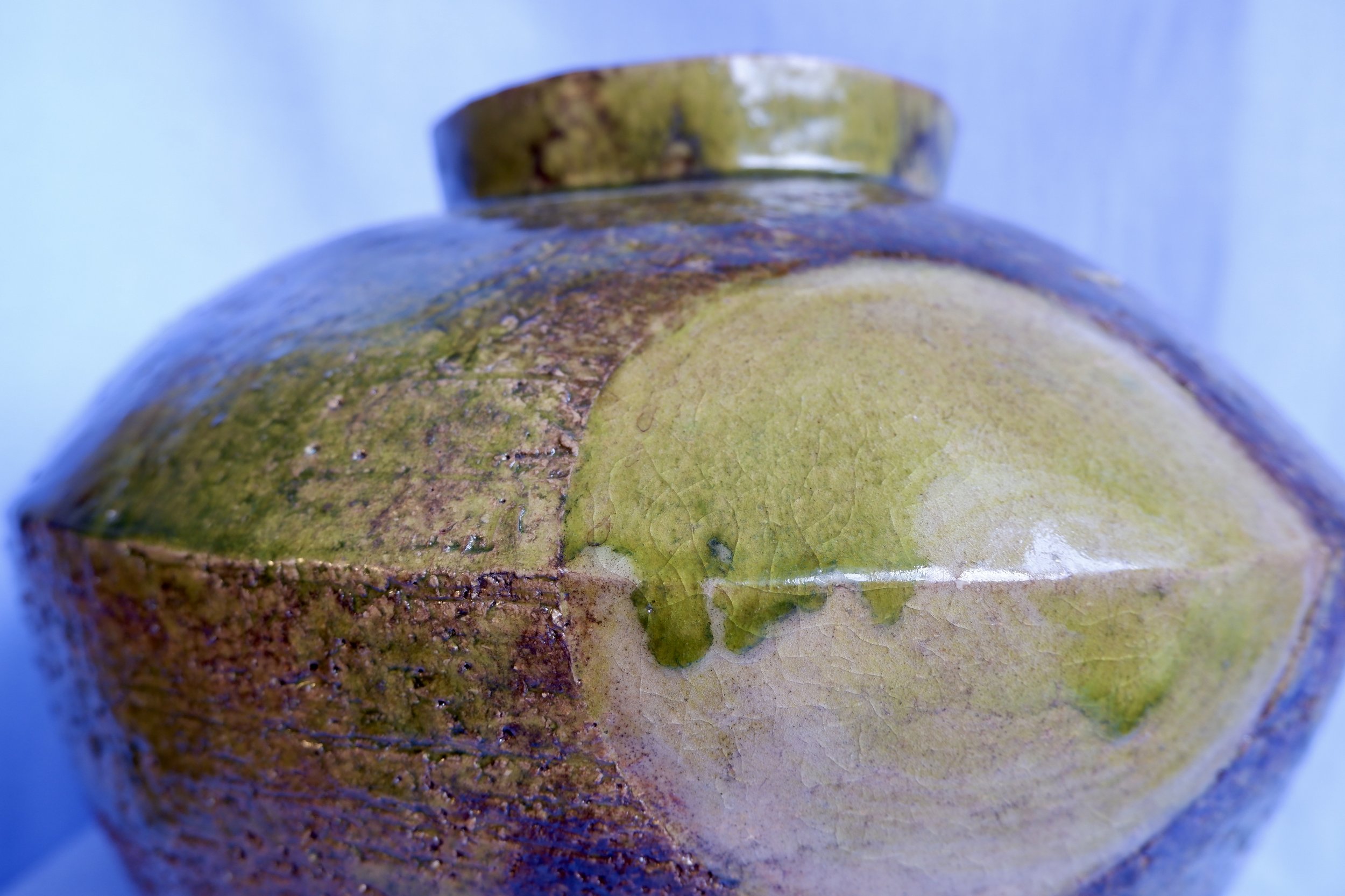 Big vase made from red clay, glazed in shades of green and brown.
