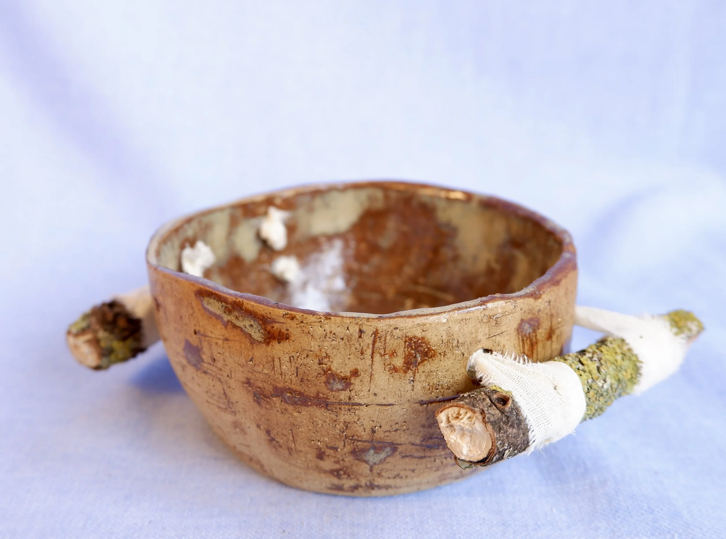Bowl made from yellow clay, bound to two branches.