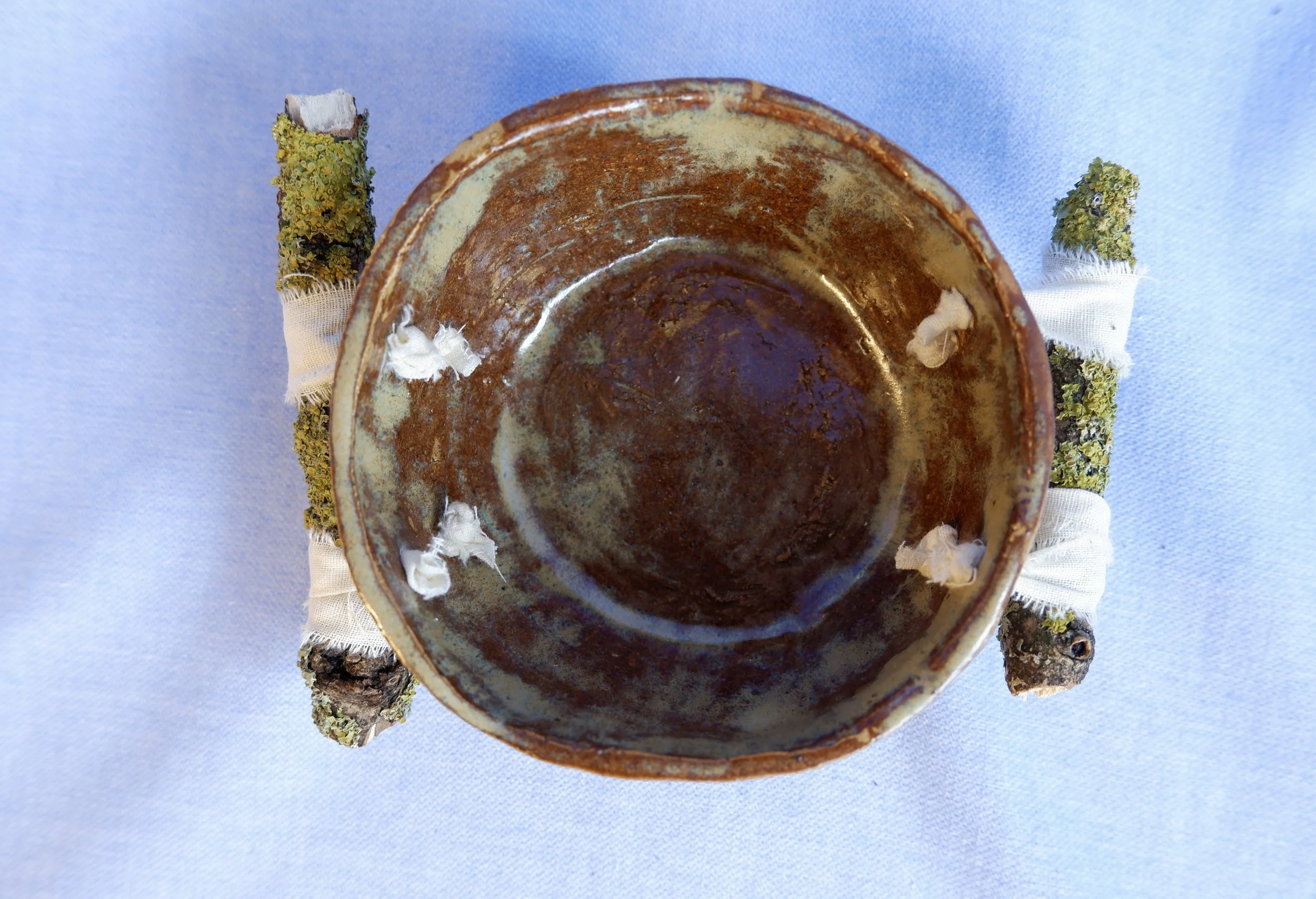Bowl made from yellow clay, bound to two branches.