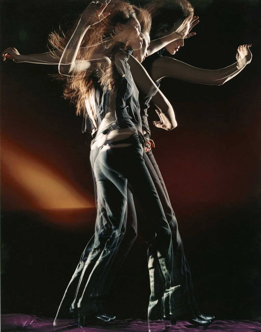 Multiple layered images of a woman with long, flowing hair, striking various poses against a dark background with light streaks.