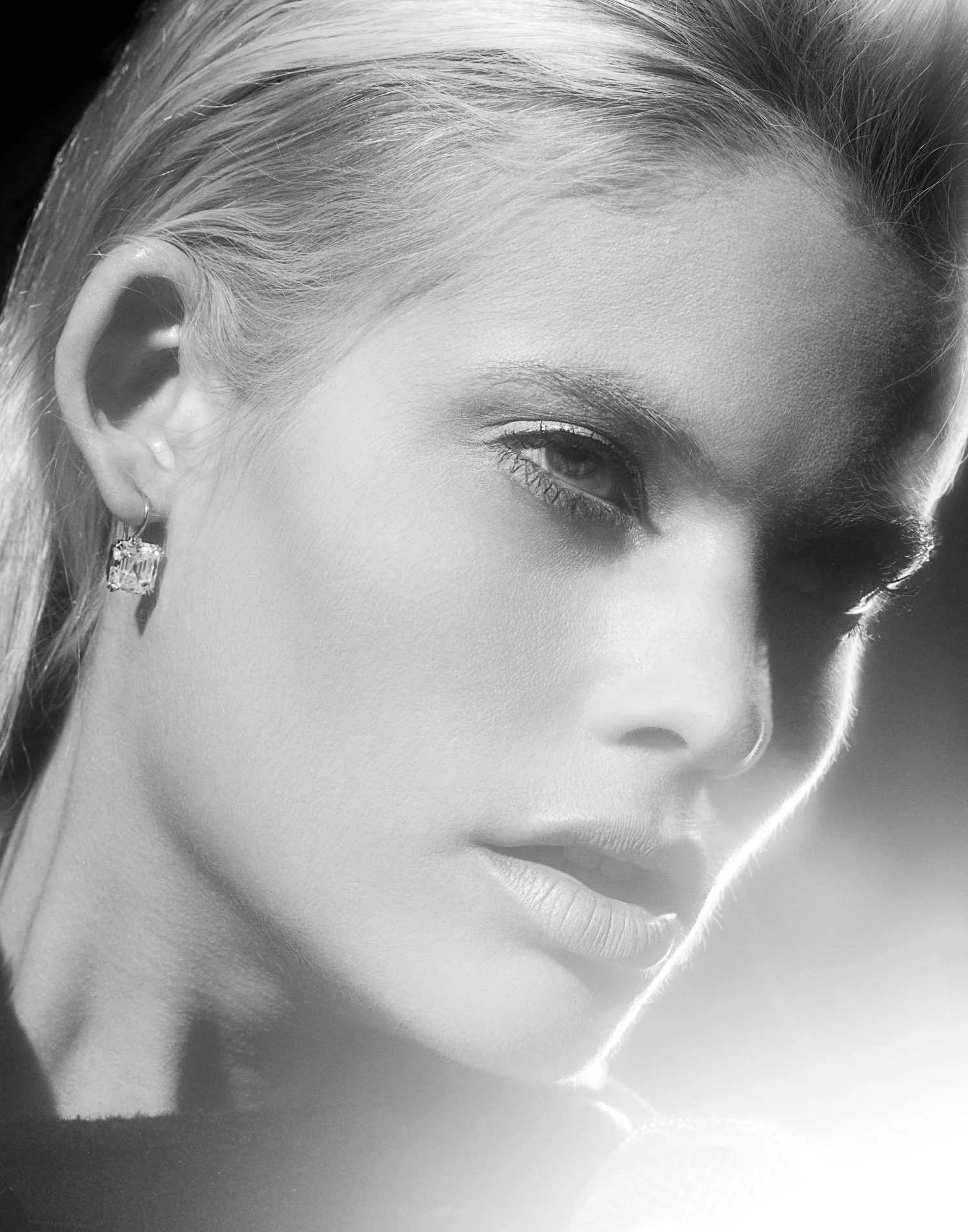 Close-up of a woman with blonde hair, wearing earrings, with her face turned slightly to the side.