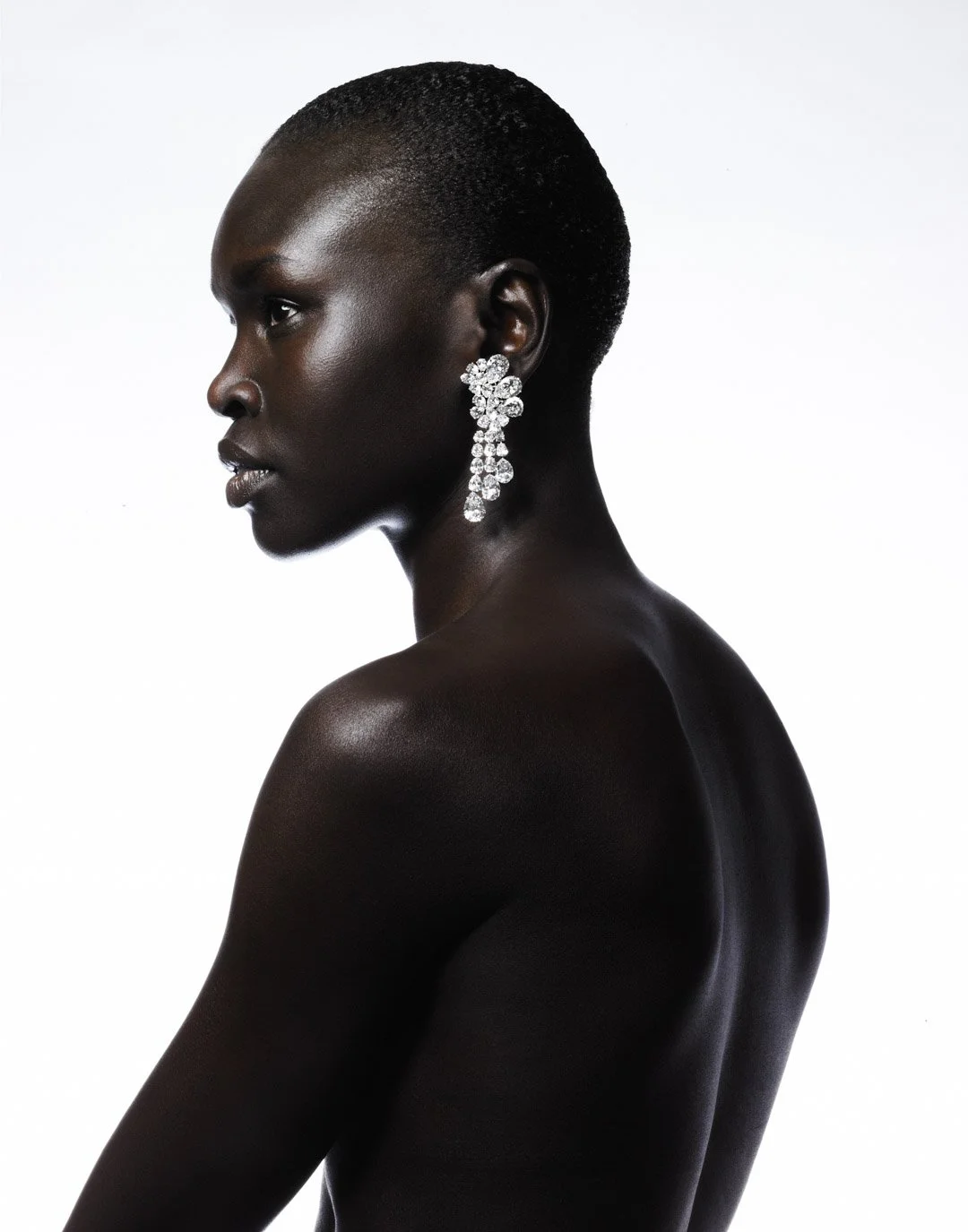 Profile portrait of a Black woman with short hair, wearing large, dangling diamond earrings, against a plain white background.