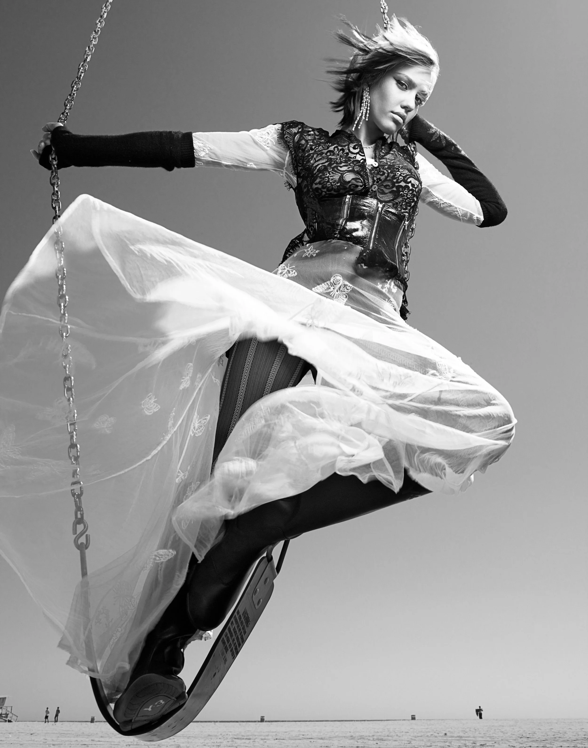 Stylish JESSICA ALBA riding a hoverboard on a beach, wearing a lace top, striped tights, and tall boots, with wind blowing through her hair.