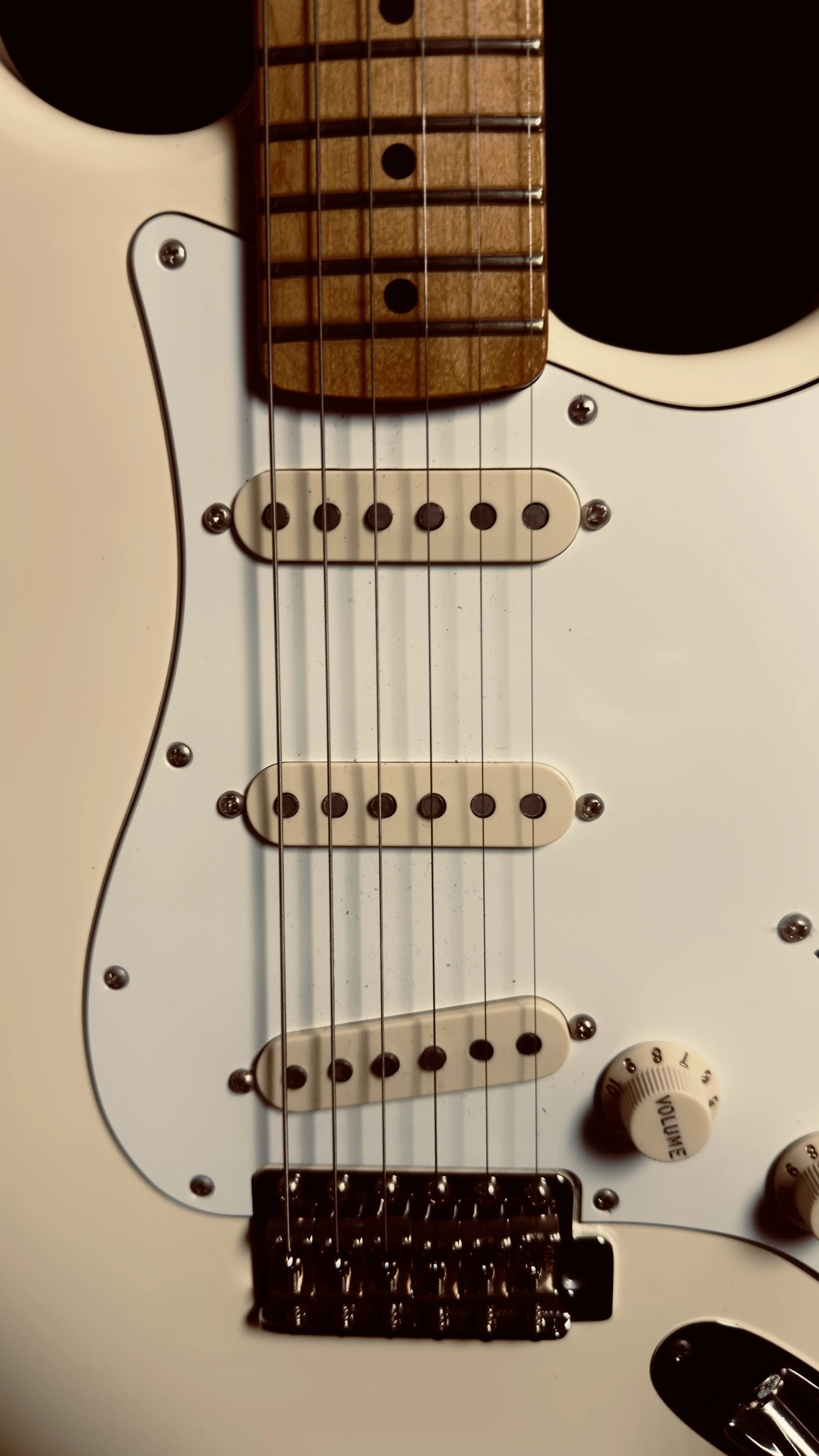 Close-up of an electric guitar's body, focusing on the pickguard, pickups, and control knobs.