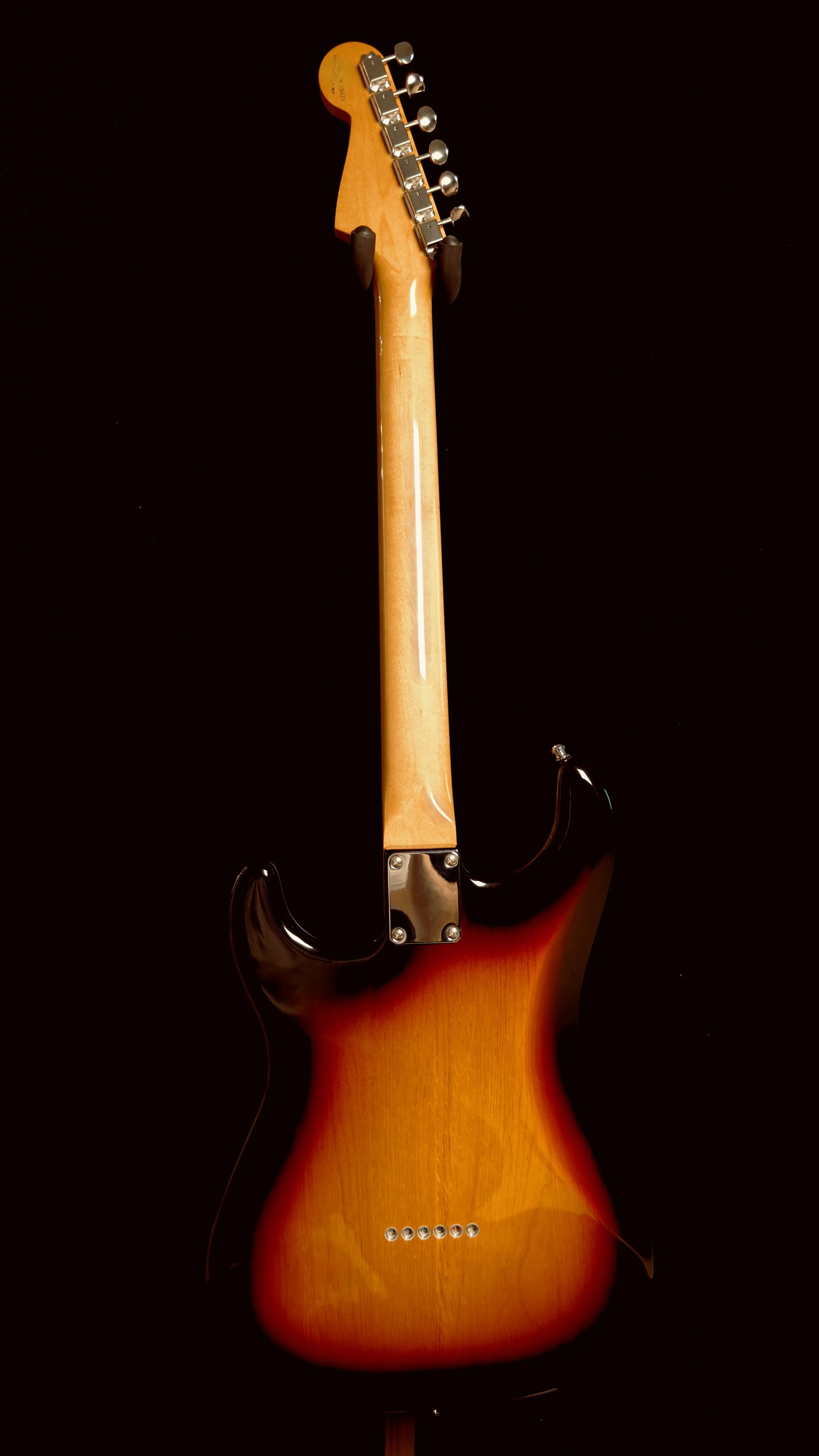 Rear view of an electric guitar with a sunburst finish on a black background.