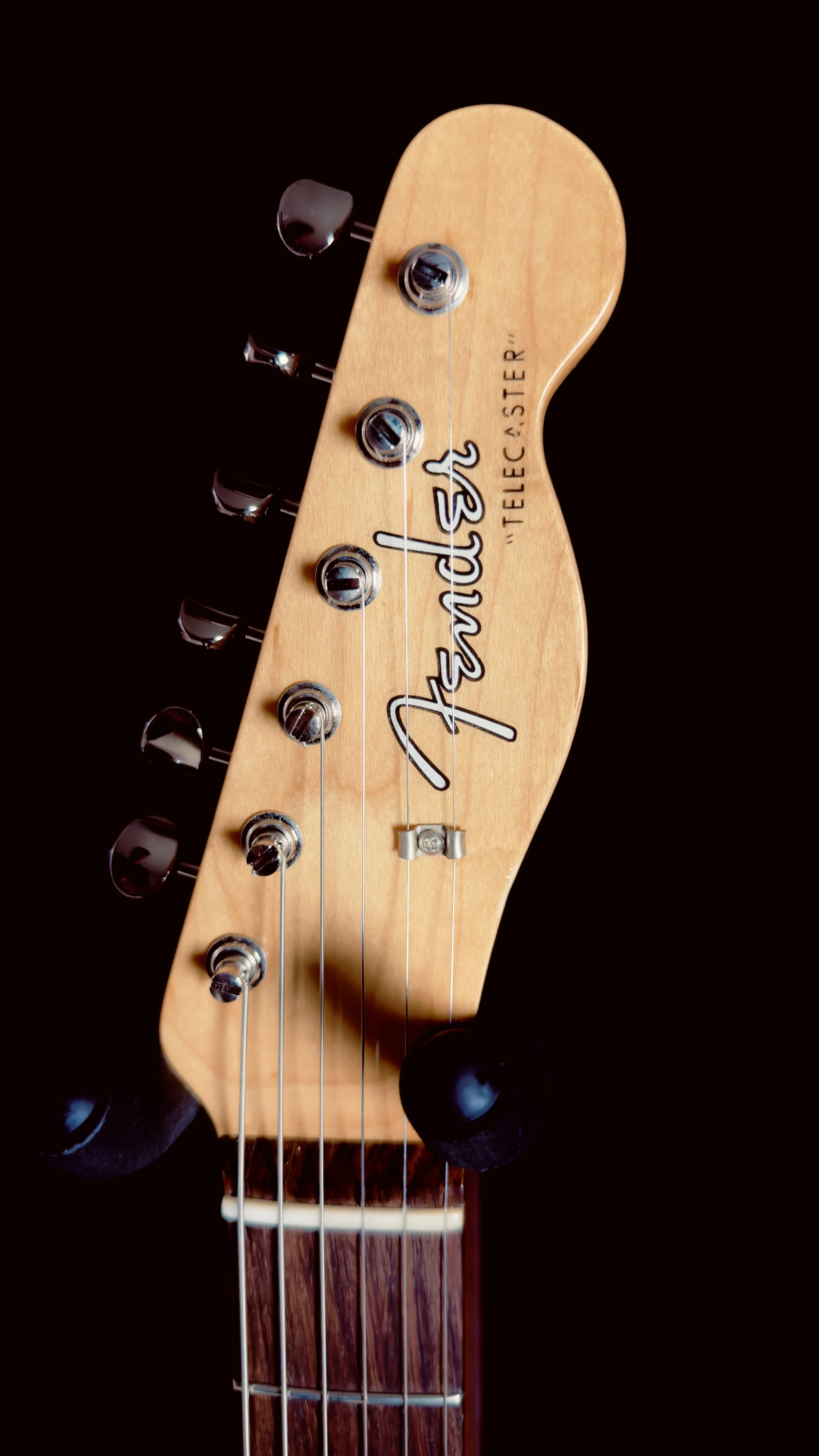 Close-up of a Fender Telecaster guitar headstock showing tuning pegs and strings.