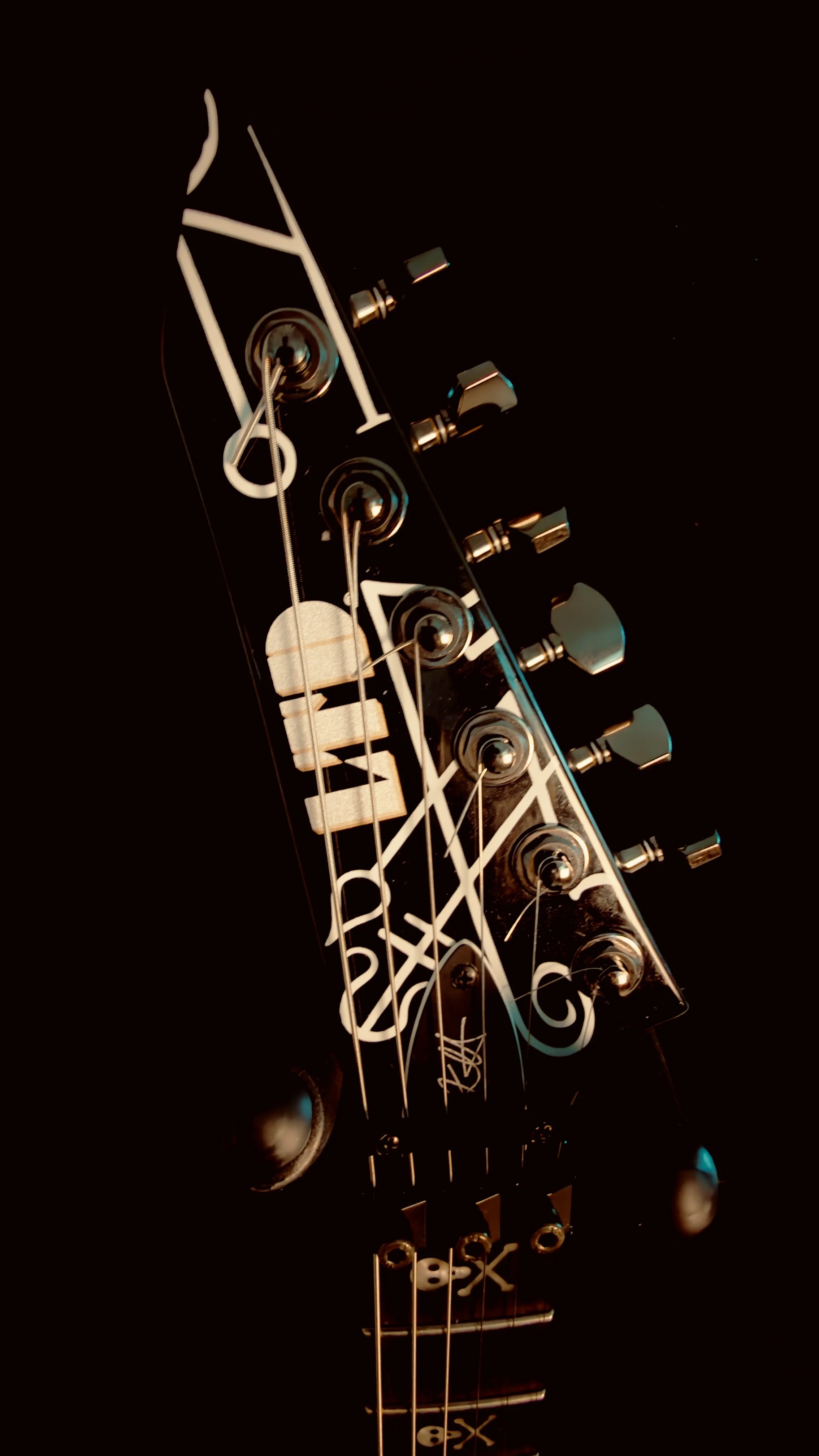 Close-up of an electric guitar's headstock with tuning pegs, strings, and branding details.