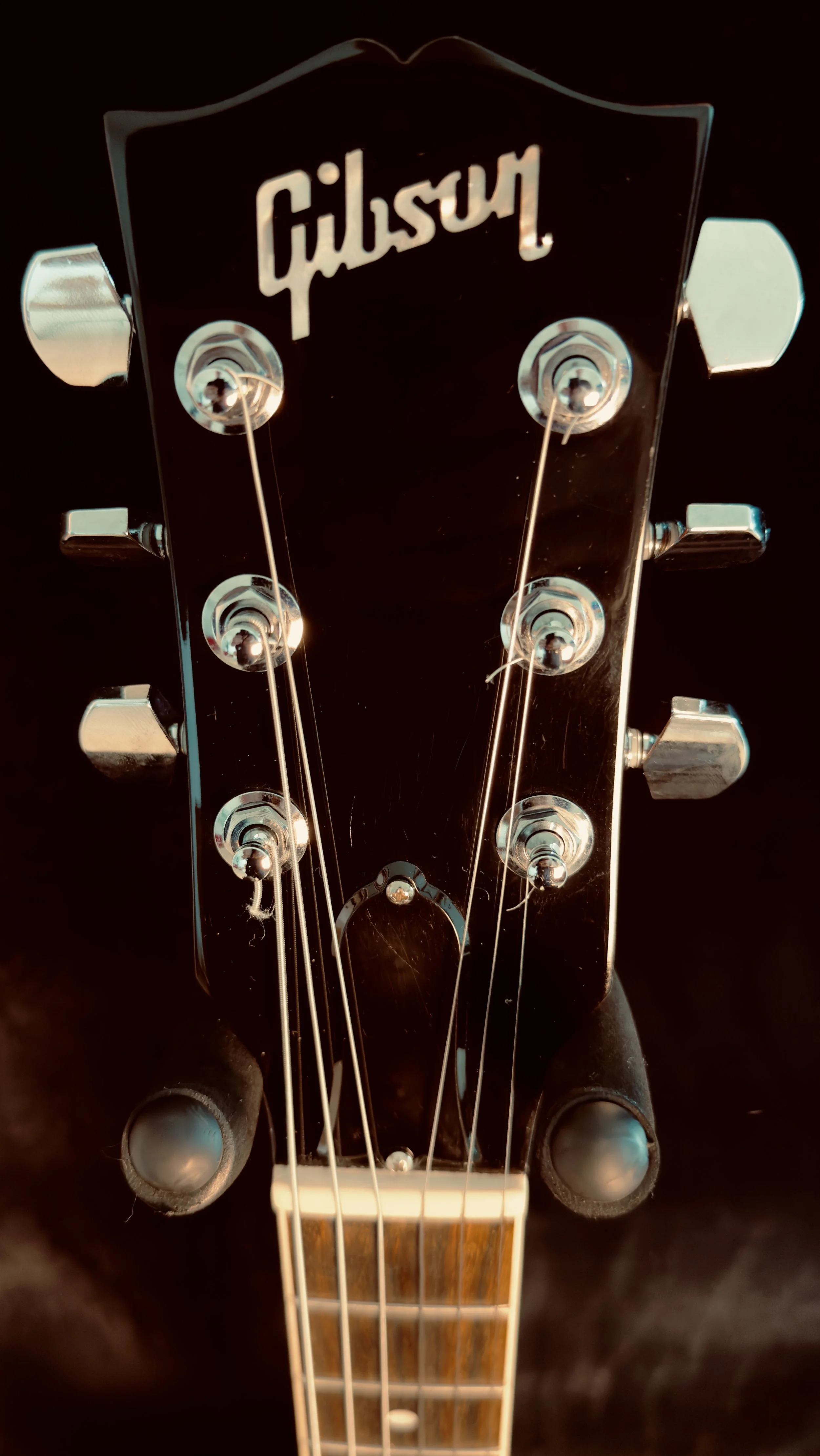 Close-up of a Gibson guitar headstock with six tuning pegs and strings.