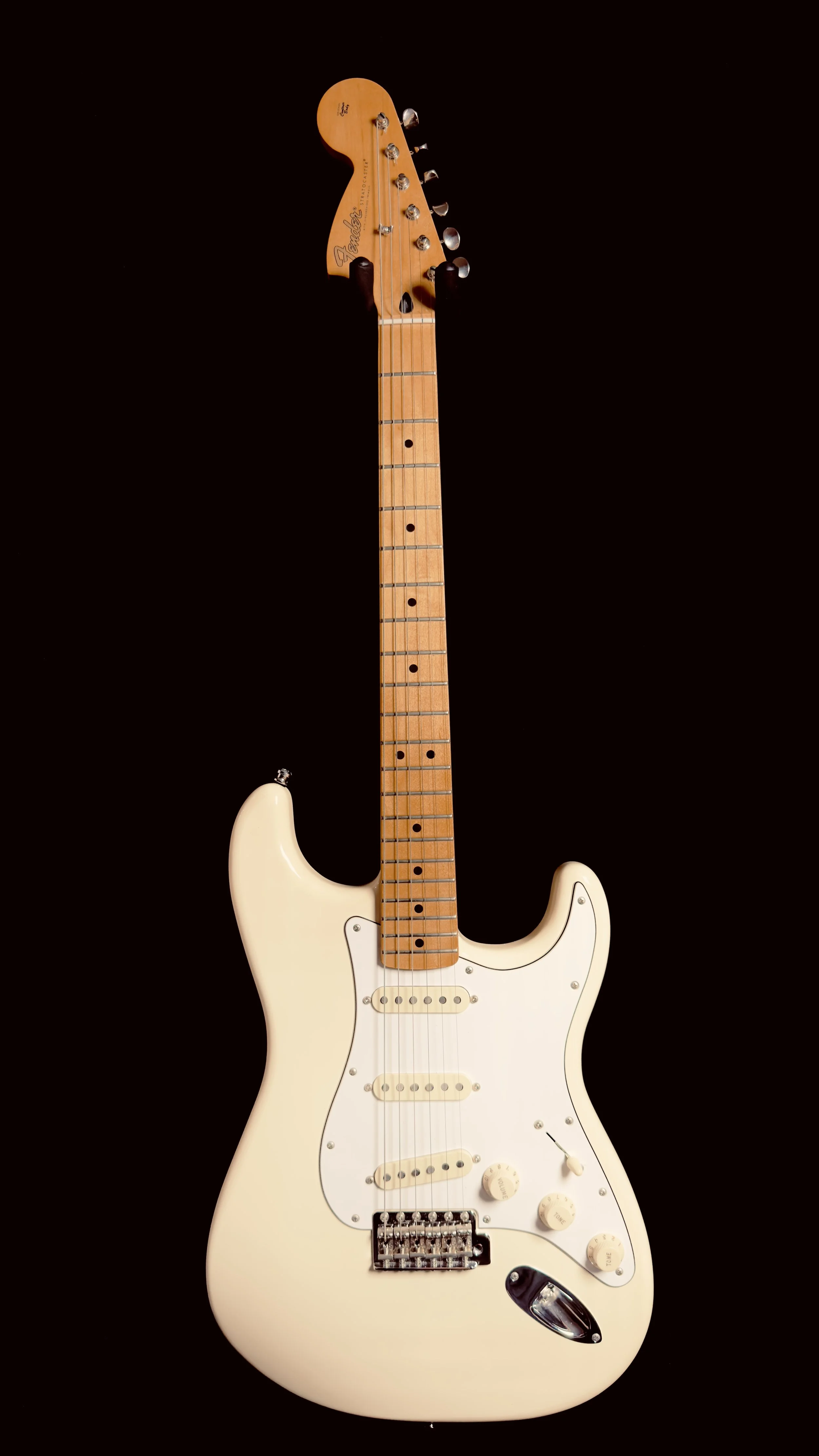 Cream-colored Fender Stratocaster electric guitar with wooden neck, against a black background.
