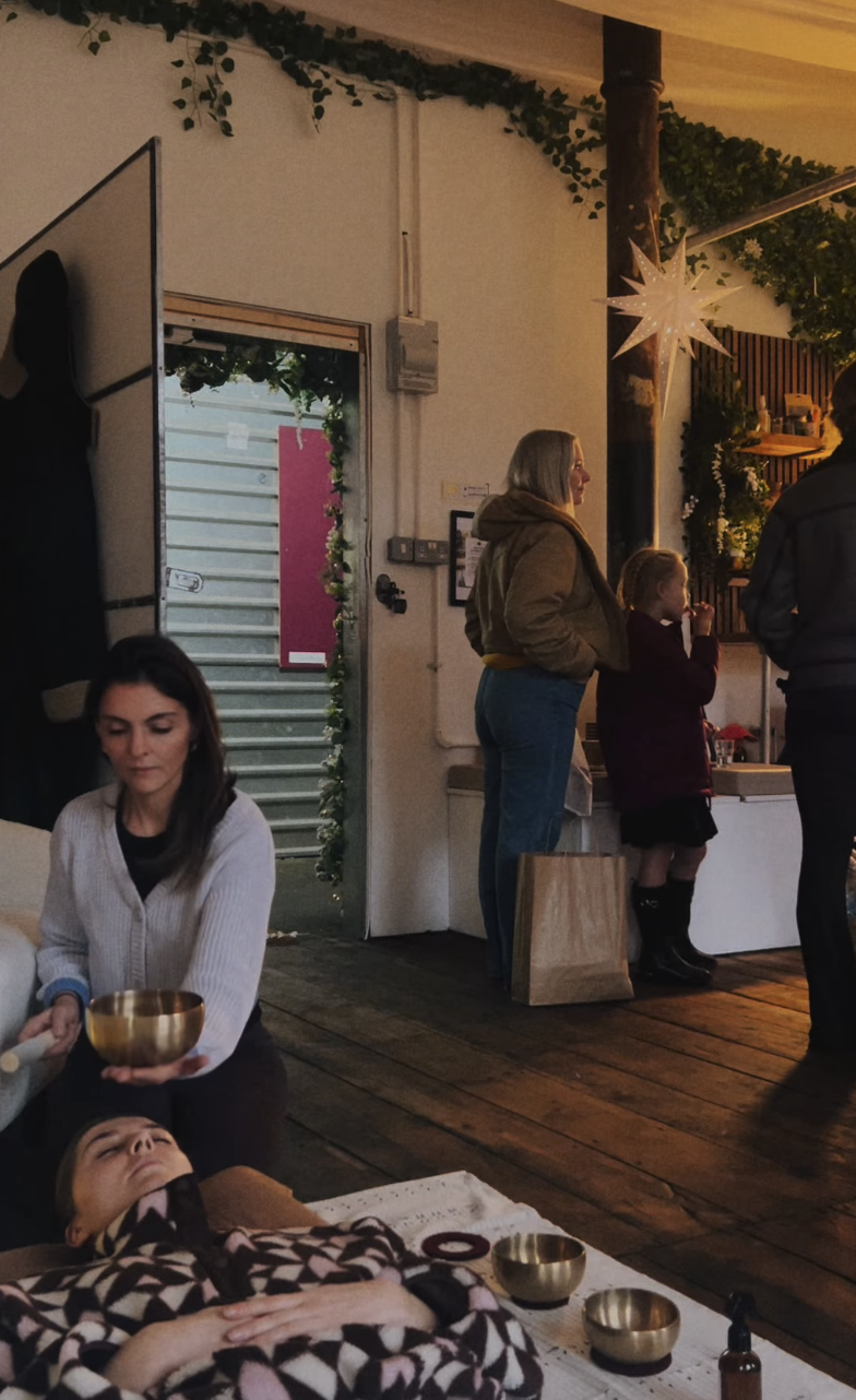 Indoor gathering with people, a woman holding a bowl, children, and decorative lights.