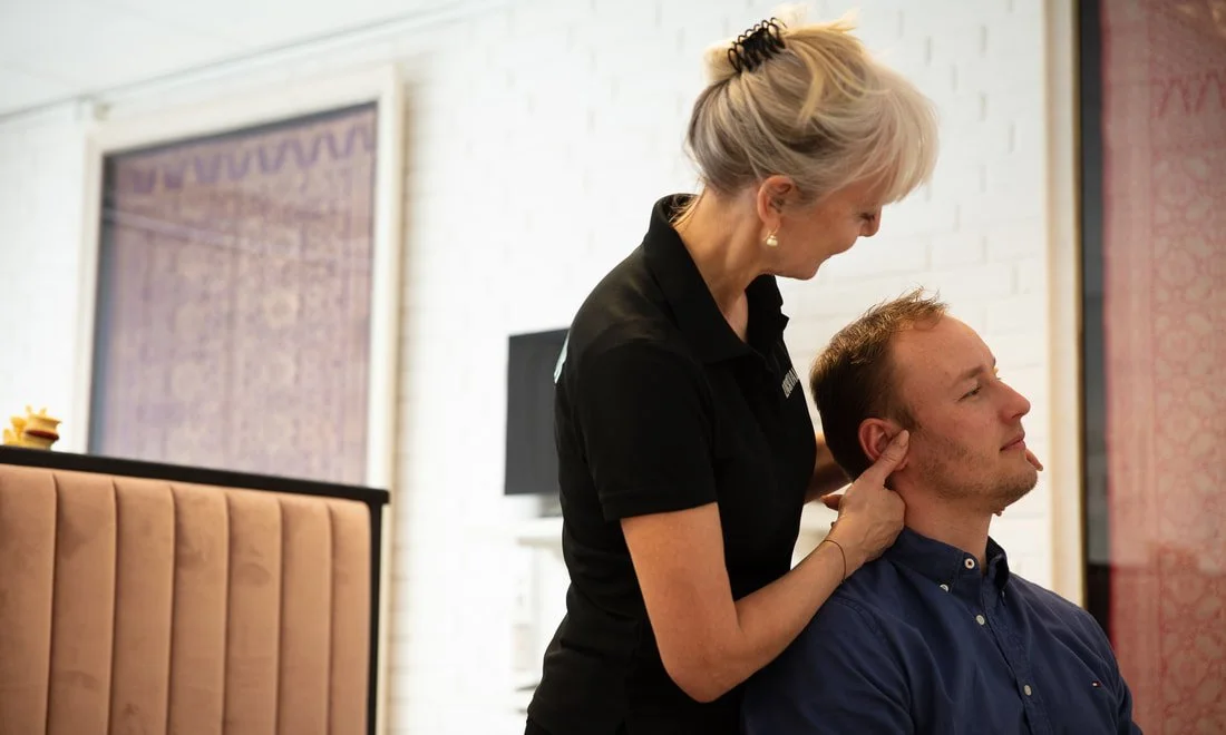 A woman providing chiropractic care to a man in a casual indoor setting.