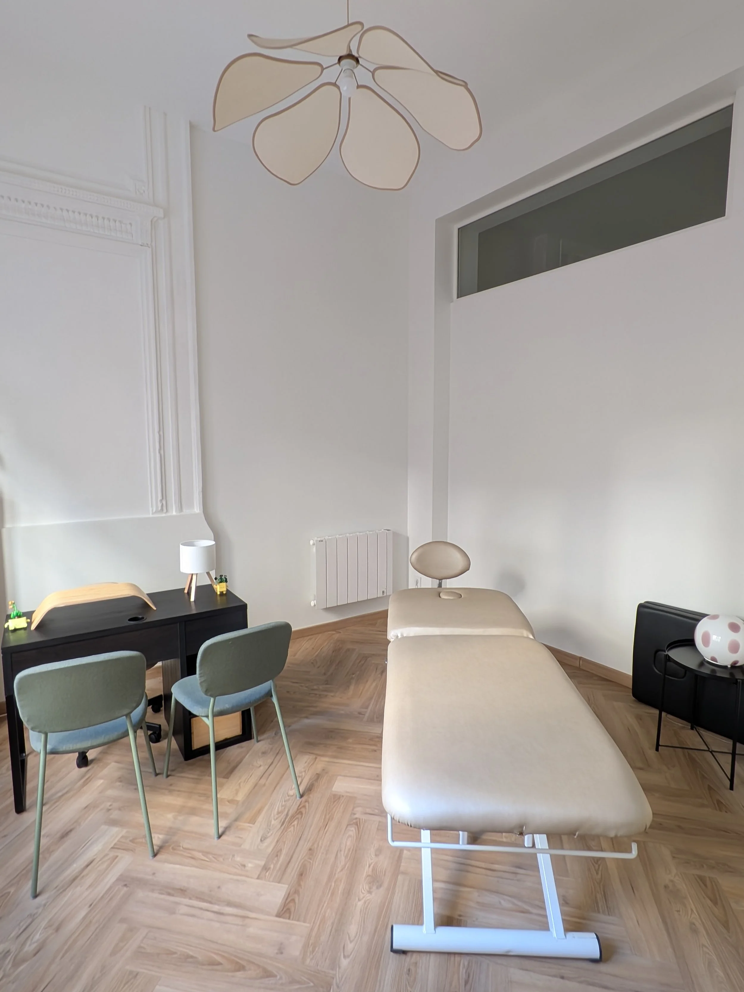 Espace de consultation d'ostéopathie avec table de soin et fauteuil d'accueil