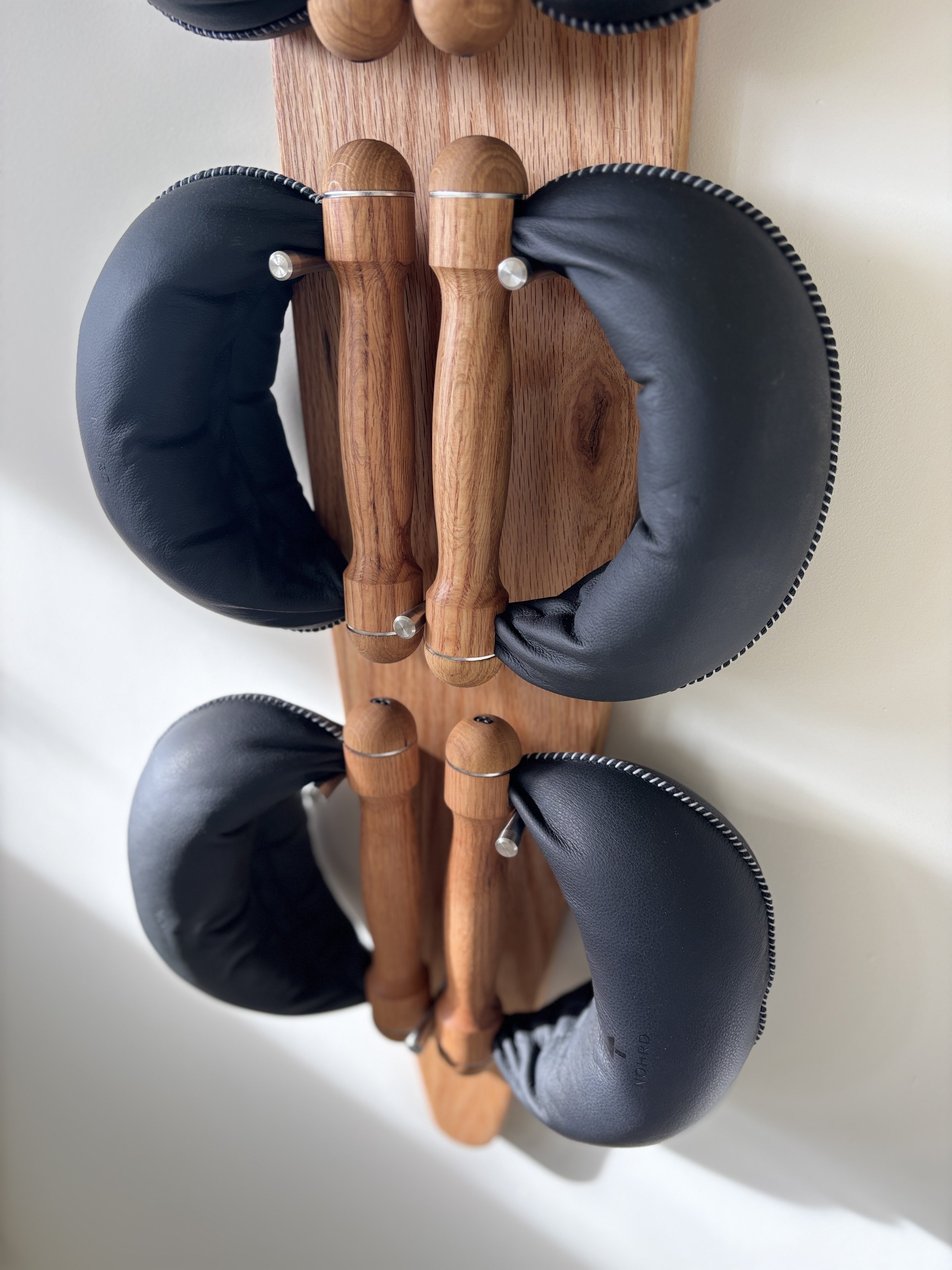 Une paire de pantalons de ski avec des poignées en bois et des protecteurs en cuir noir, fixés sur une planche en bois.