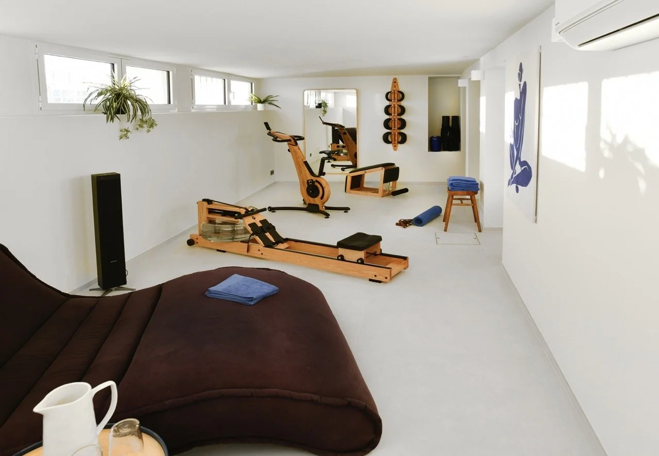 Salle de sport avec appareils de cardio, yoga et décoration zen.