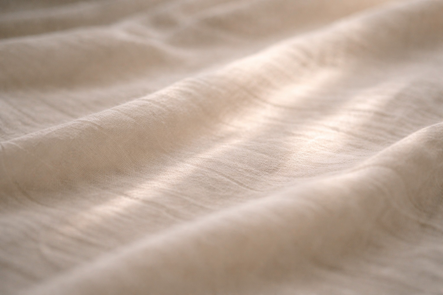 Close-up of a light-colored, soft fabric with gentle folds and smooth texture.