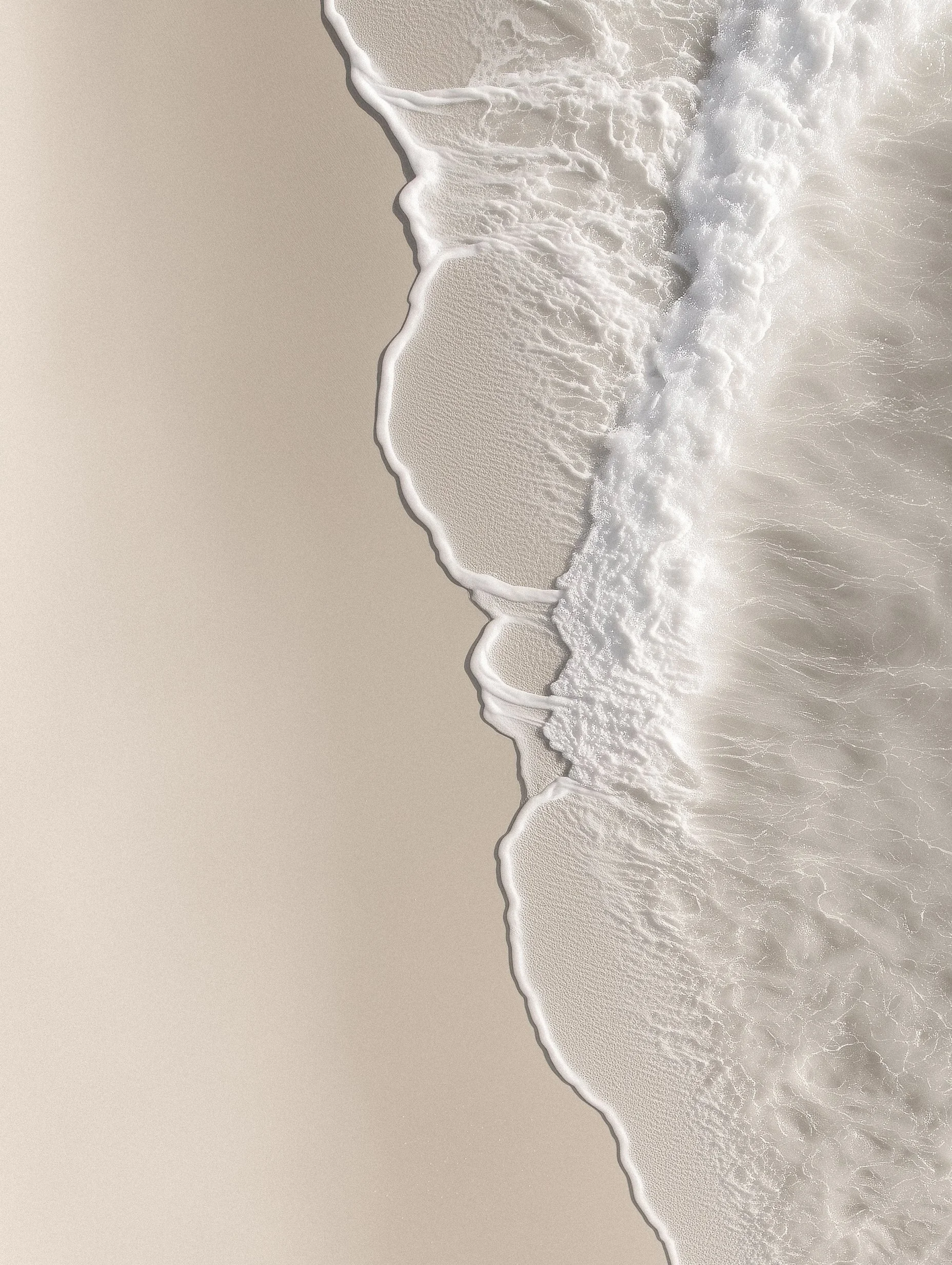 Aerial view of a sandy beach with gentle waves washing onto the shore.