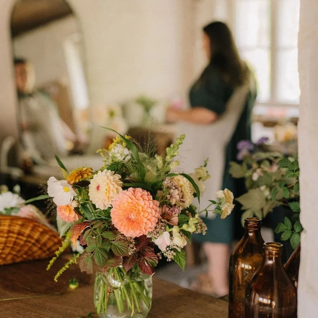 Alt="Kukkakimppu lasipurkissa puisella pöydällä"