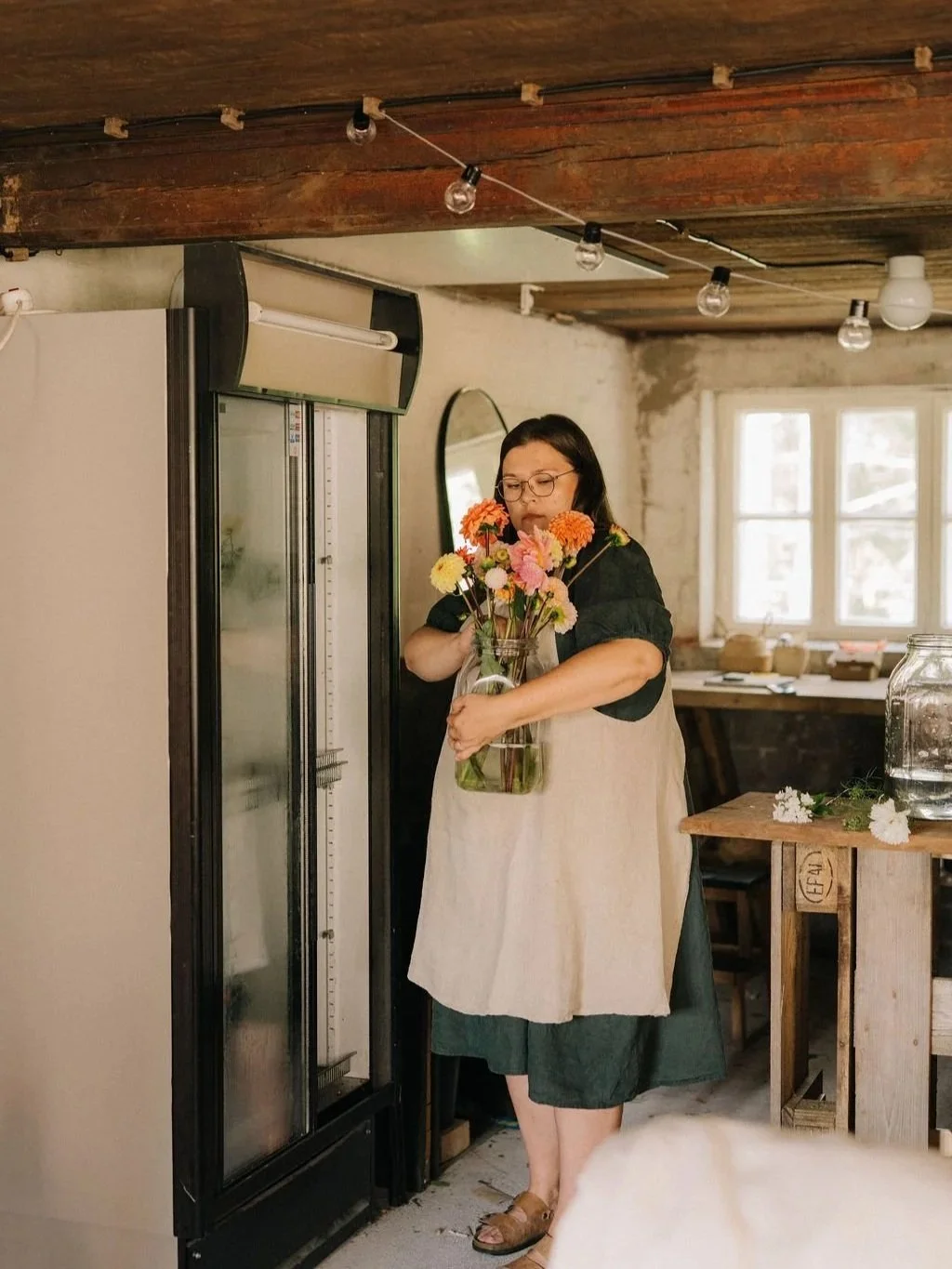 Alt="Nainen kantaa leikkokukkia sylissä"