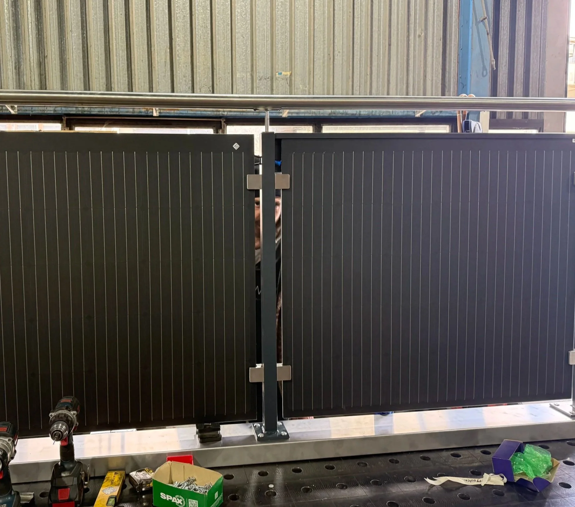 Ein Mitarbeiter arbeitet hinter einer schwarzen Solaranlagen-Klemme im Werk, mit Werkzeugen und Materialien auf der Arbeitsfläche im Vordergrund.