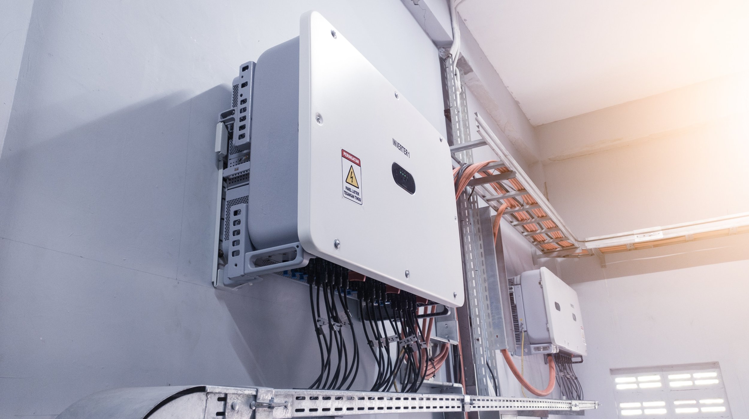 Inverter und Kabel in einer technischen Installation, vermutlich in einem Gebäude für Solarenergie oder elektrische Systeme.