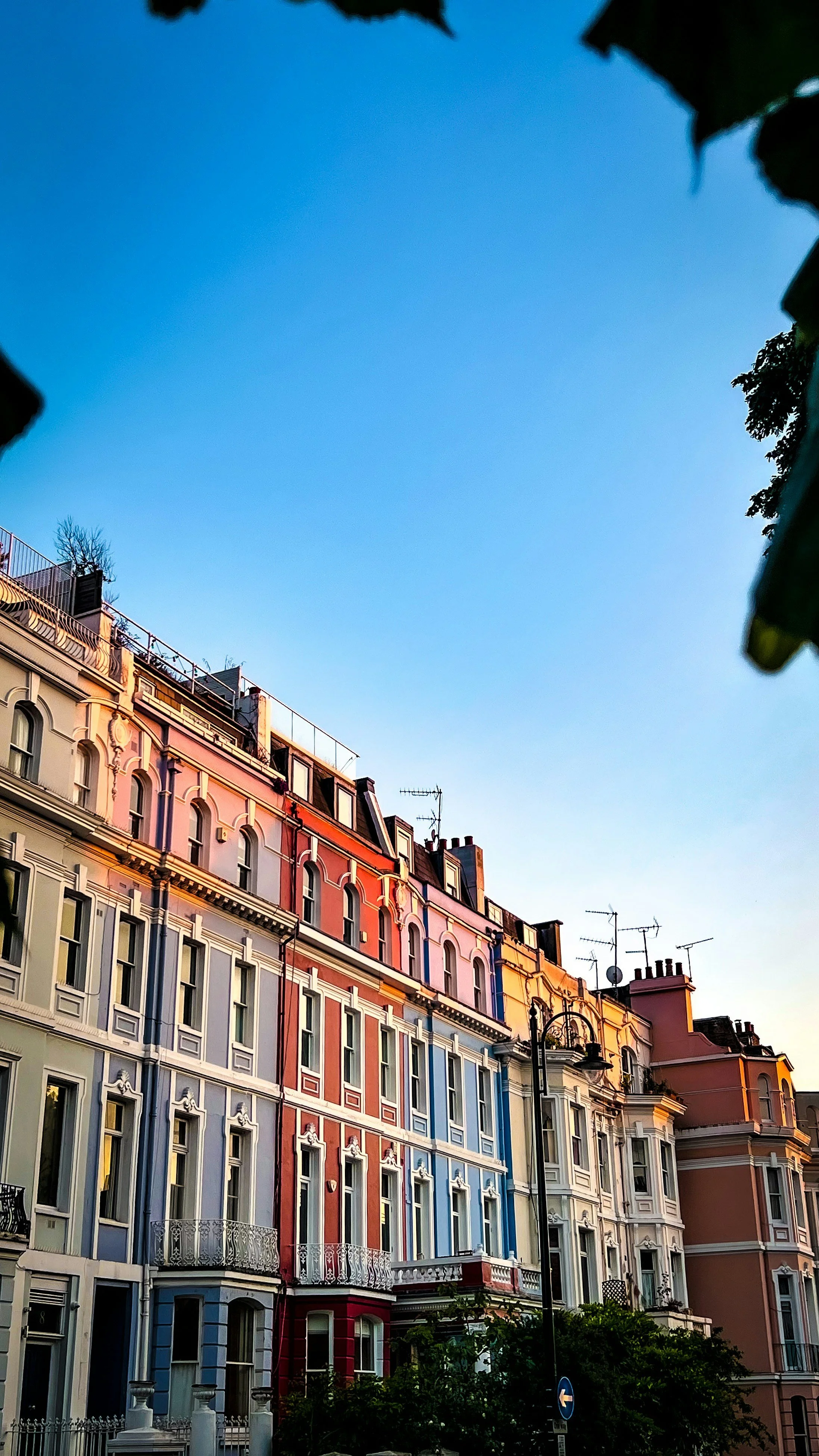 Colorful, ornate apartment buildings with bay windows, balconies, and a clear sky at dusk.