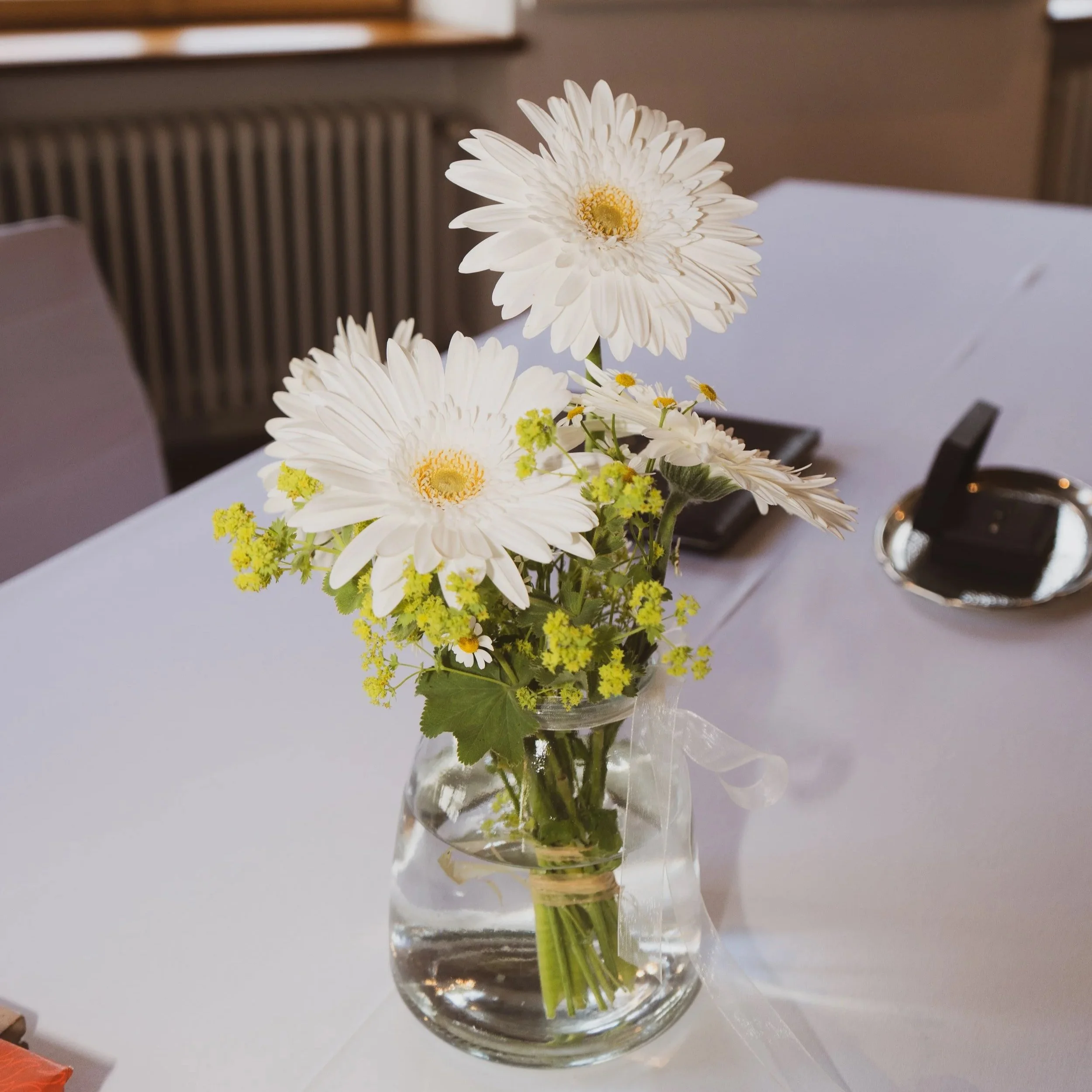 Weiße Blumen in einem Glasvasen auf einem Tisch.