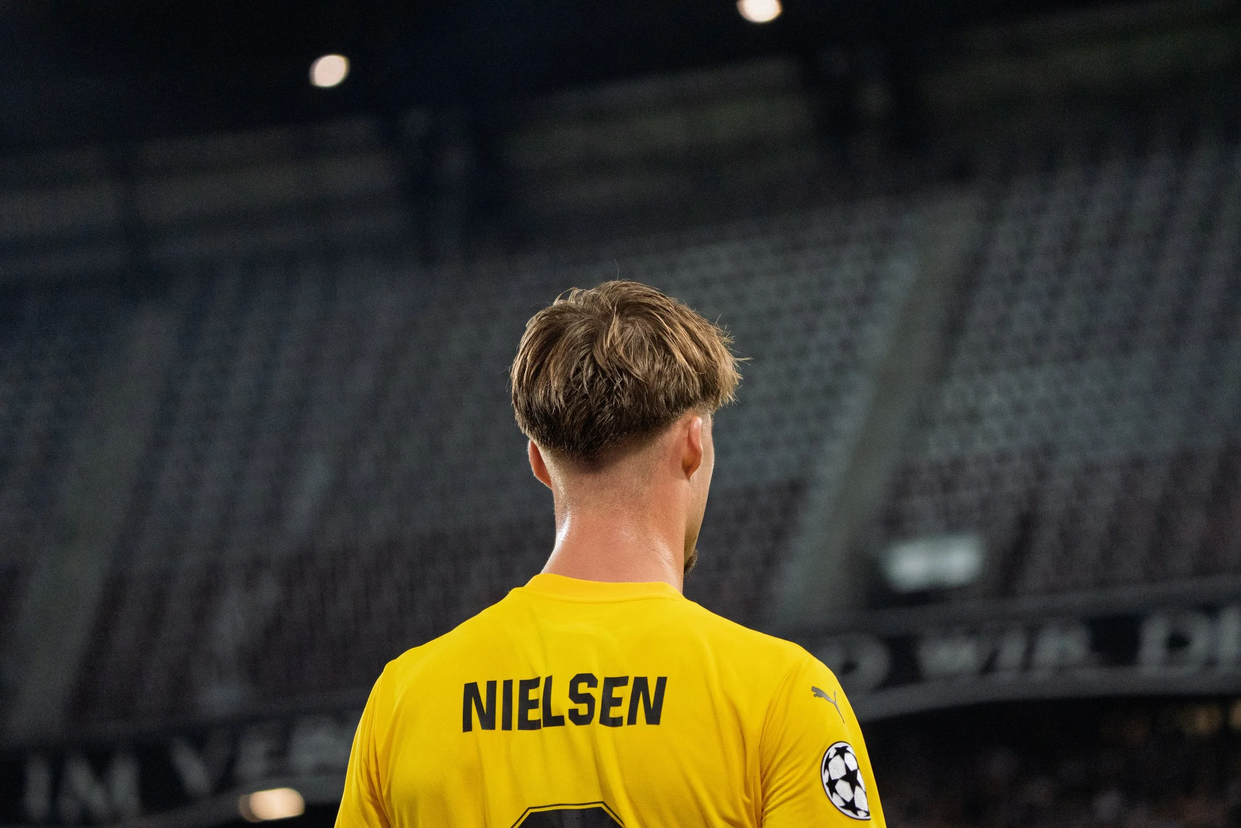 Fußballspieler mit gelbem Trikot und dem Namen Nielsen auf dem Rücken, auf einem Fußballfeld bei einem Spiel in der Champions League.