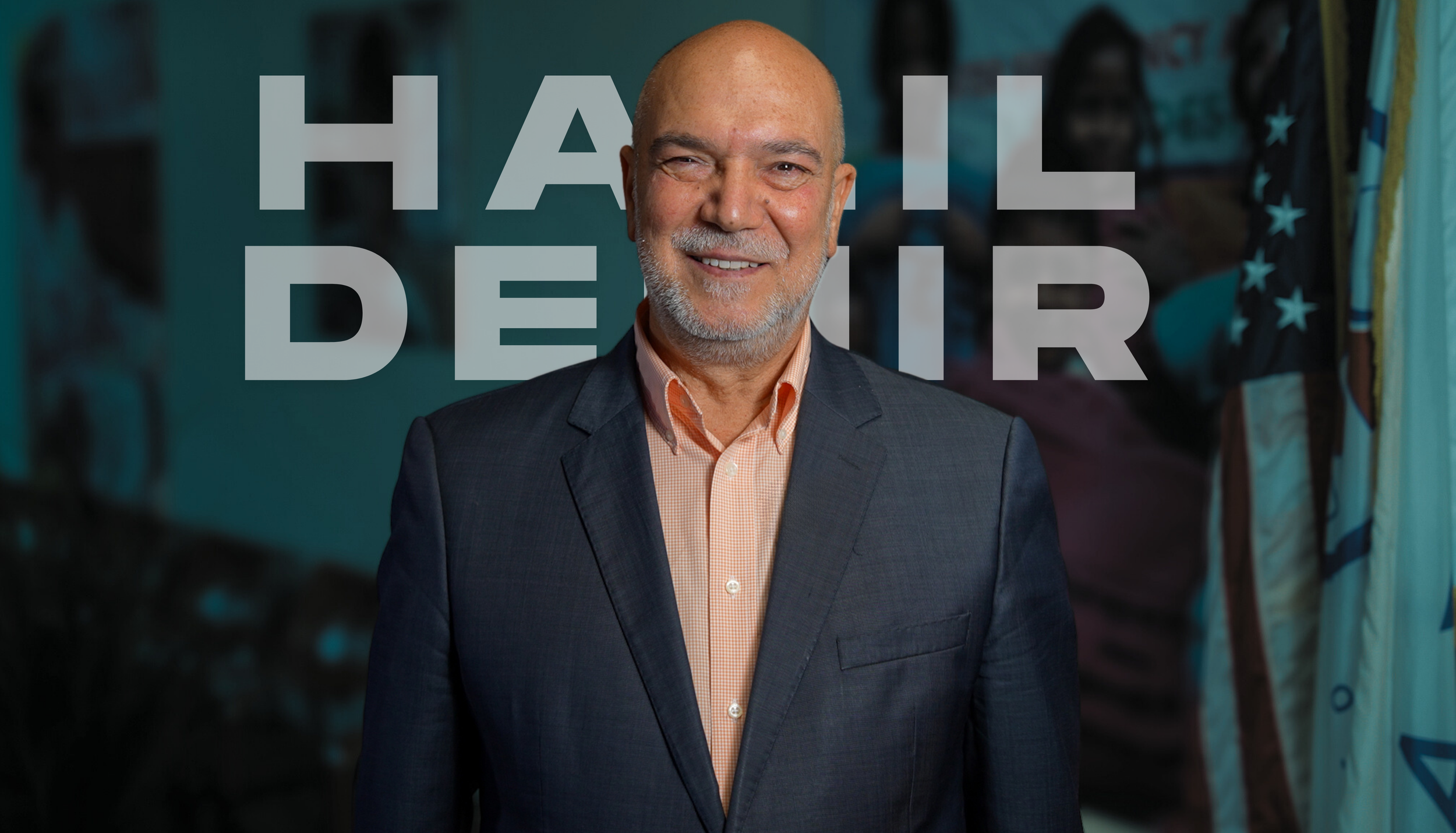 Halil Demir smiling and  wearing a dark suit and light orange shirt, standing in front of a blue background with large gray text that reads 'HALIL DEMIR'.