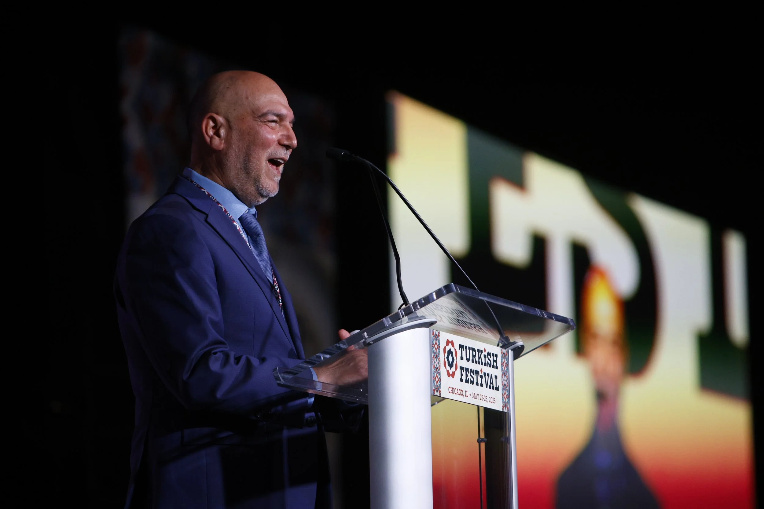 Halil Demir in a blue suit speaking at a podium during a Turkish festival event in Chicago, IL, on May 25-26, 2023.