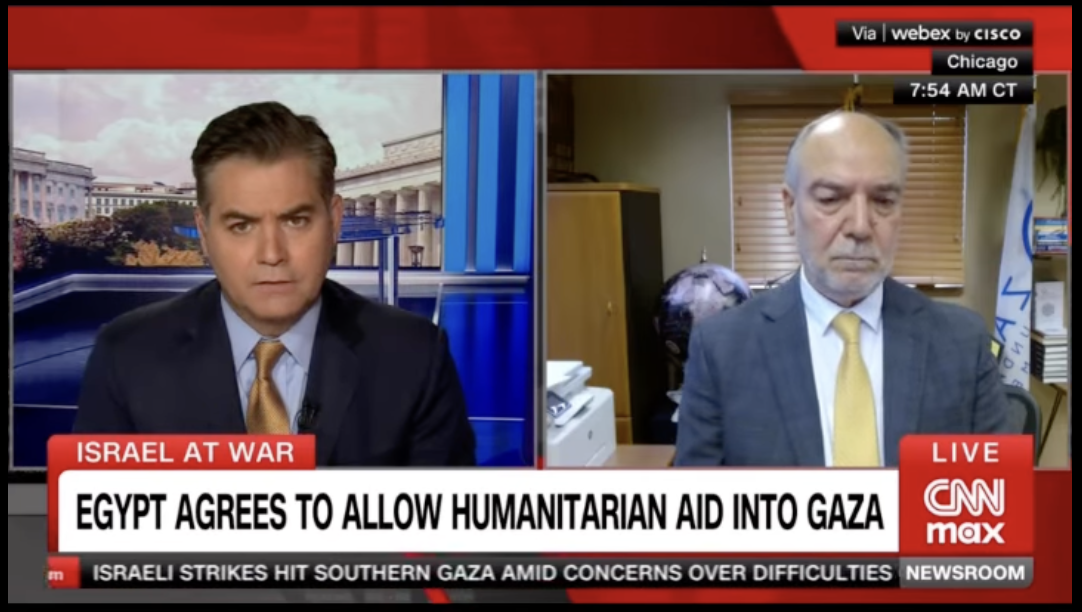 Screenshot of a CNN Max news broadcast about Israel and Gaza, showing two men in a split-screen interview. The man on the left is in a studio with a cityscape background, wearing a dark suit and gold tie. The man on the right appears to be in an office, wearing a gray suit and yellow tie.