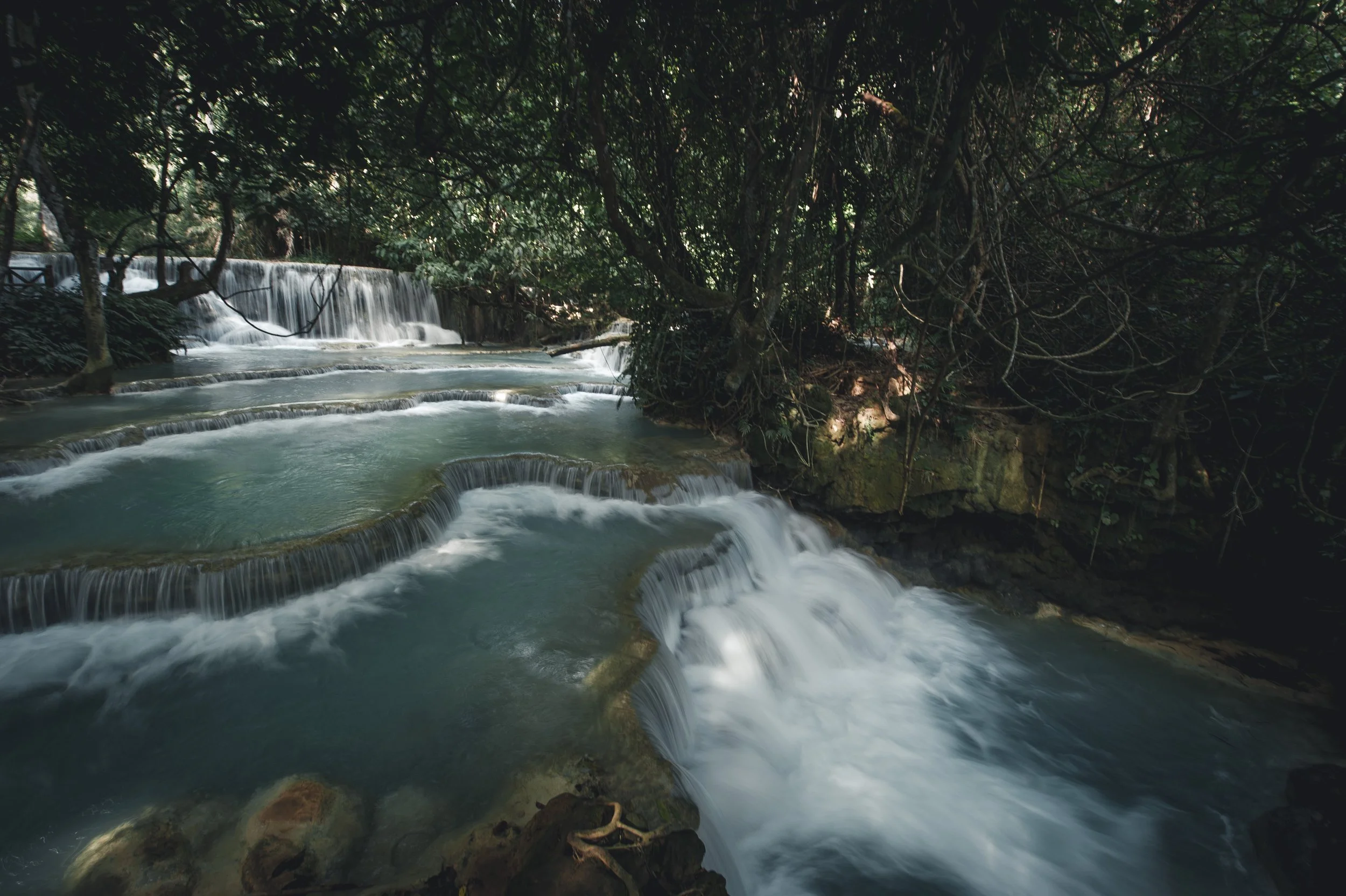 Mehrstufiger Wasserfall in einem dichten, grün bewachsenen Dschungel, mit Wasser, das sanft über Steine fließt. Reise in exotische Länder. Hochwertige Fotografie.