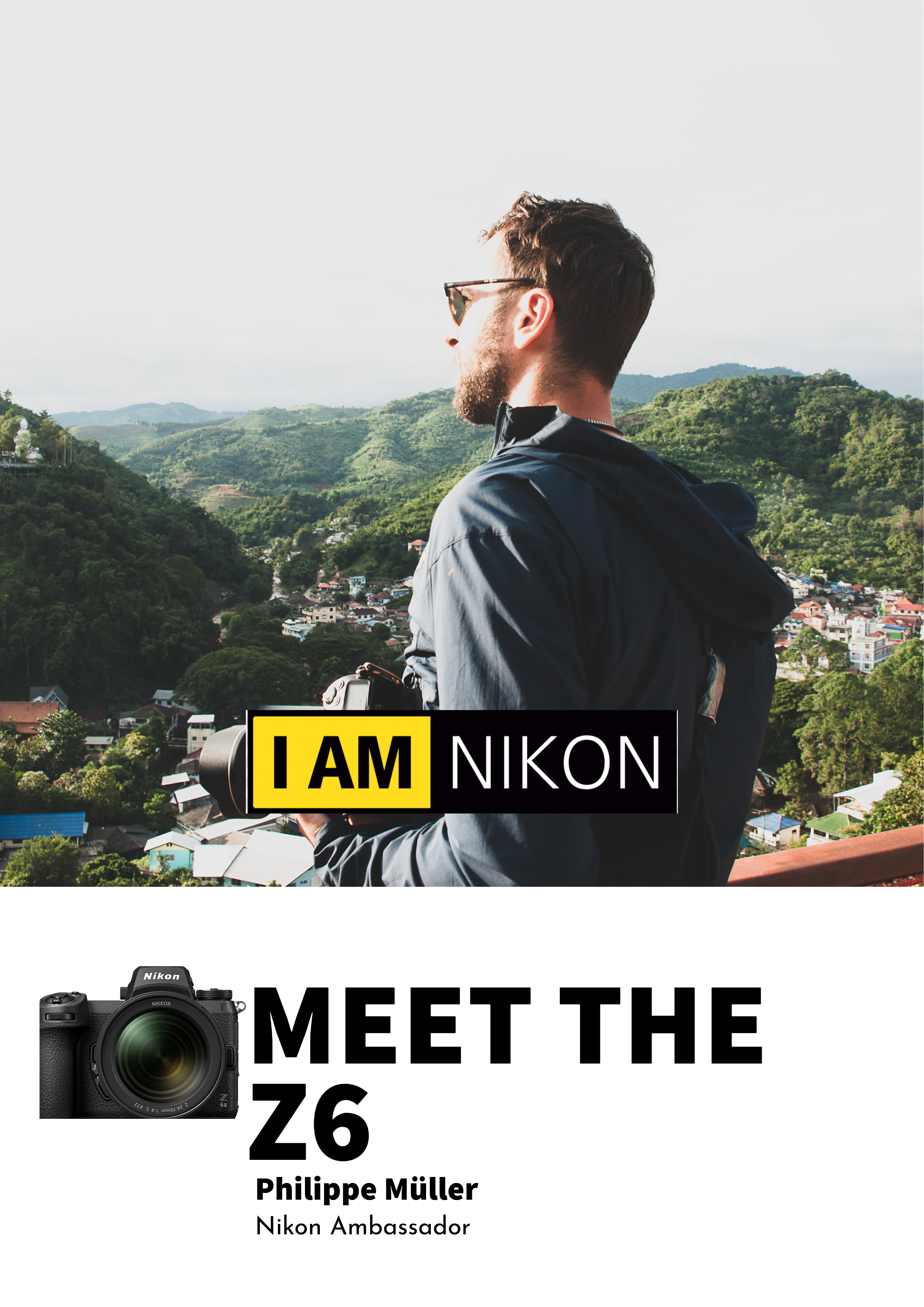 Ein Mann mit Brille und dunkler Jacke steht auf einer Aussichtsplattform, blickt in die Ferne auf eine grüne hügelige Landschaft, im Vordergrund eine Kamera.