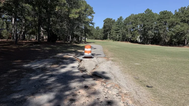 Cart path section under renovation with an orange traffic barrel beside the fairway