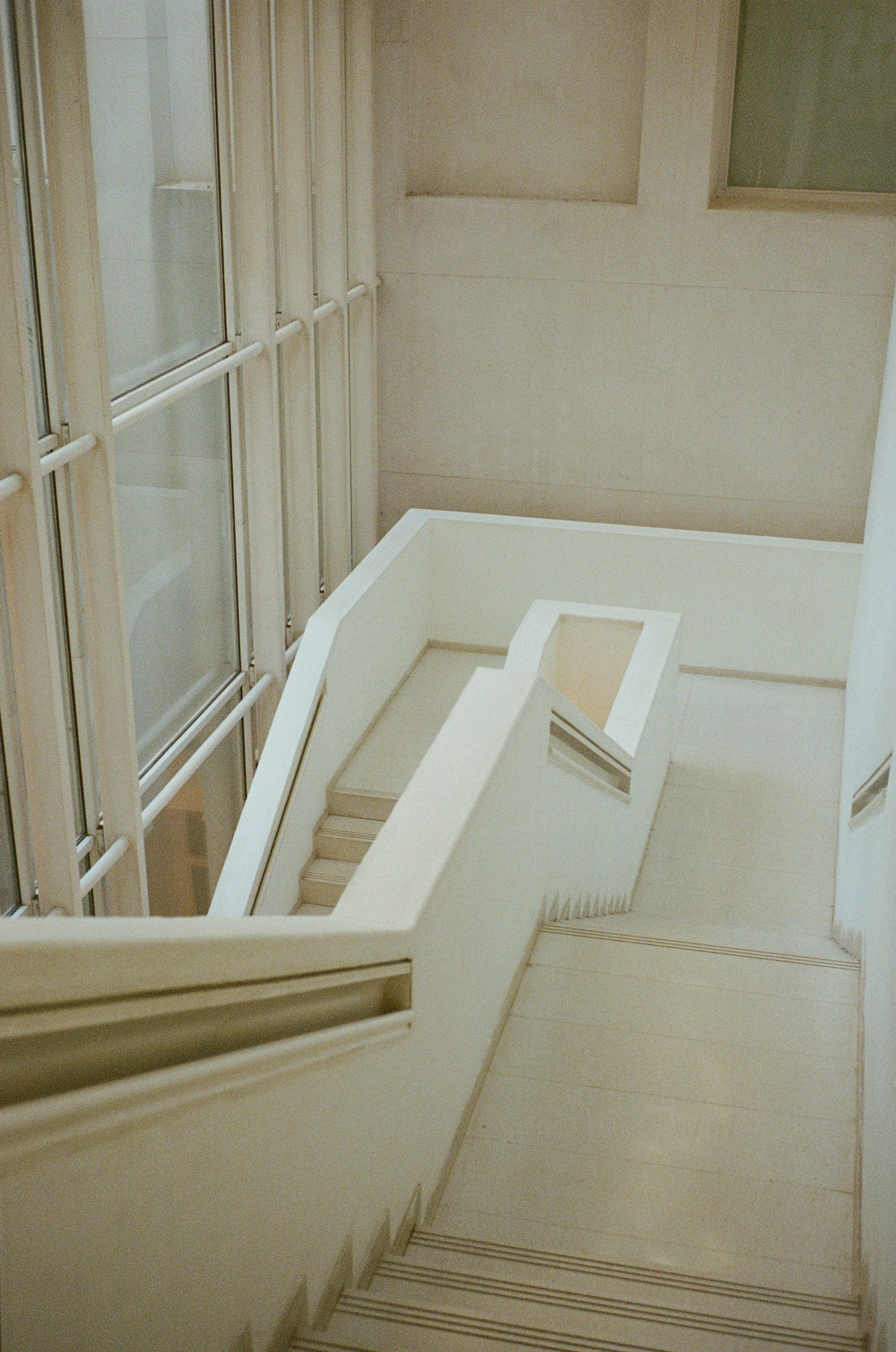 Interior stairwell with beige walls, white railings, and glass windows.