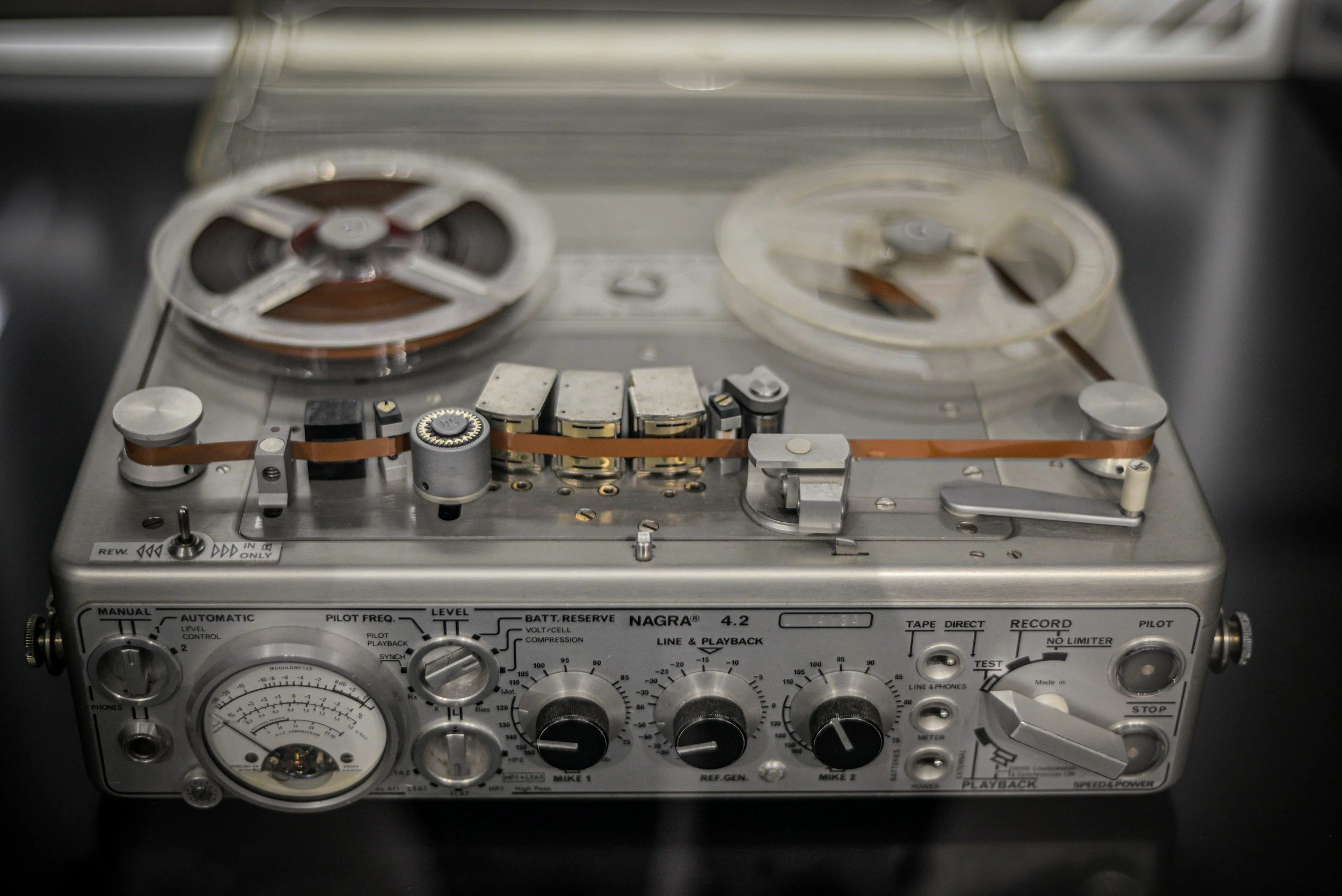 Close-up of a vintage reel-to-reel tape recorder with various controls, knobs, and meters.